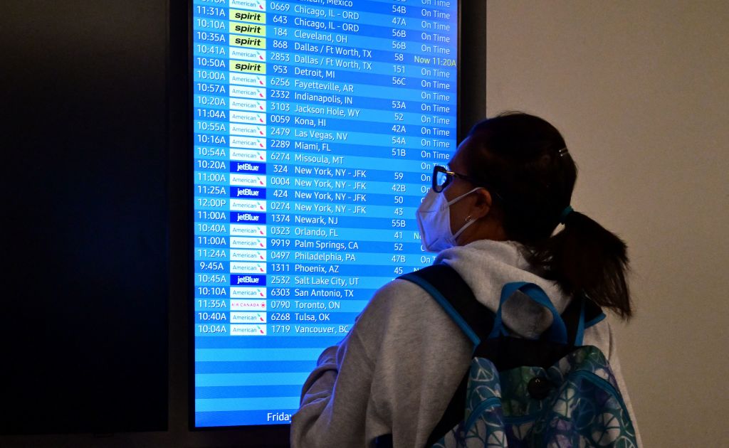 A woman wearing a face mask checks for flight arrivals at Los Angeles International Airport on July 1, 2022. (Frederic J. Brown/AFP—Getty Images)