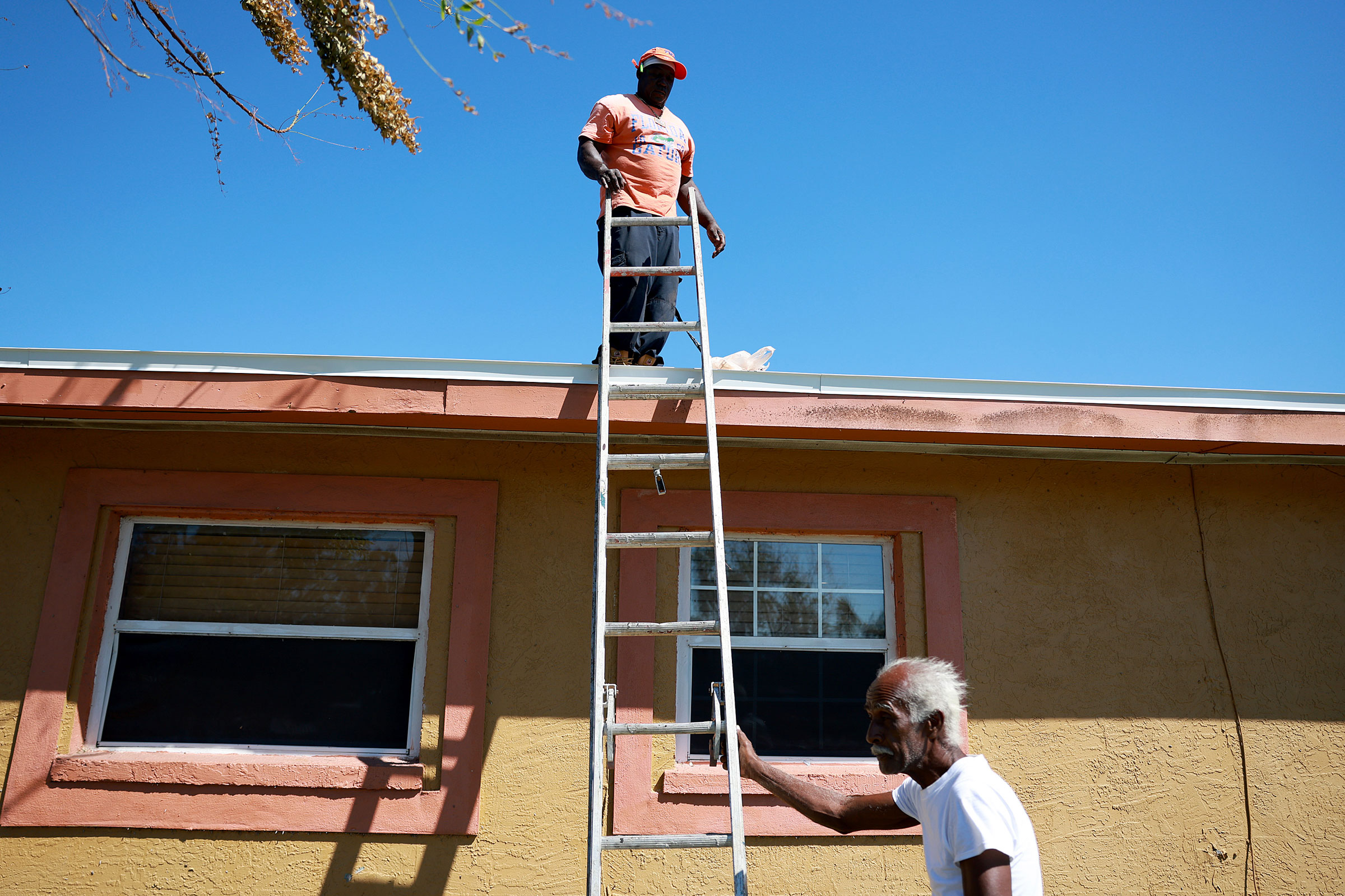 Johnny Lee Kerney and Francisco Mancheo fix a roof on a damaged home in Fort Myers, Fla., on Oct. 7, 2022.