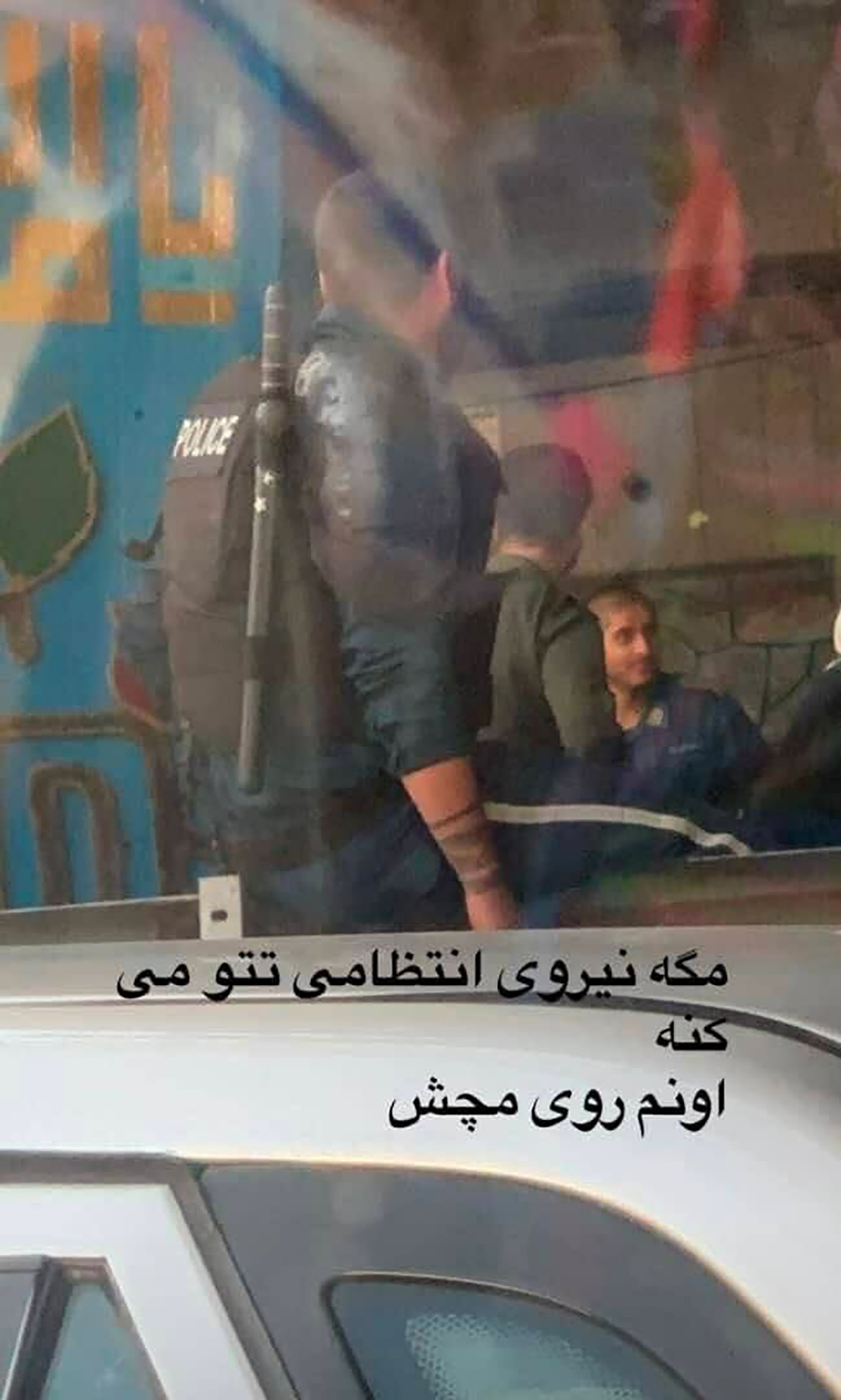 Text says, in Persian, “Does the police force use tattoos? Of all places on their wrist?”