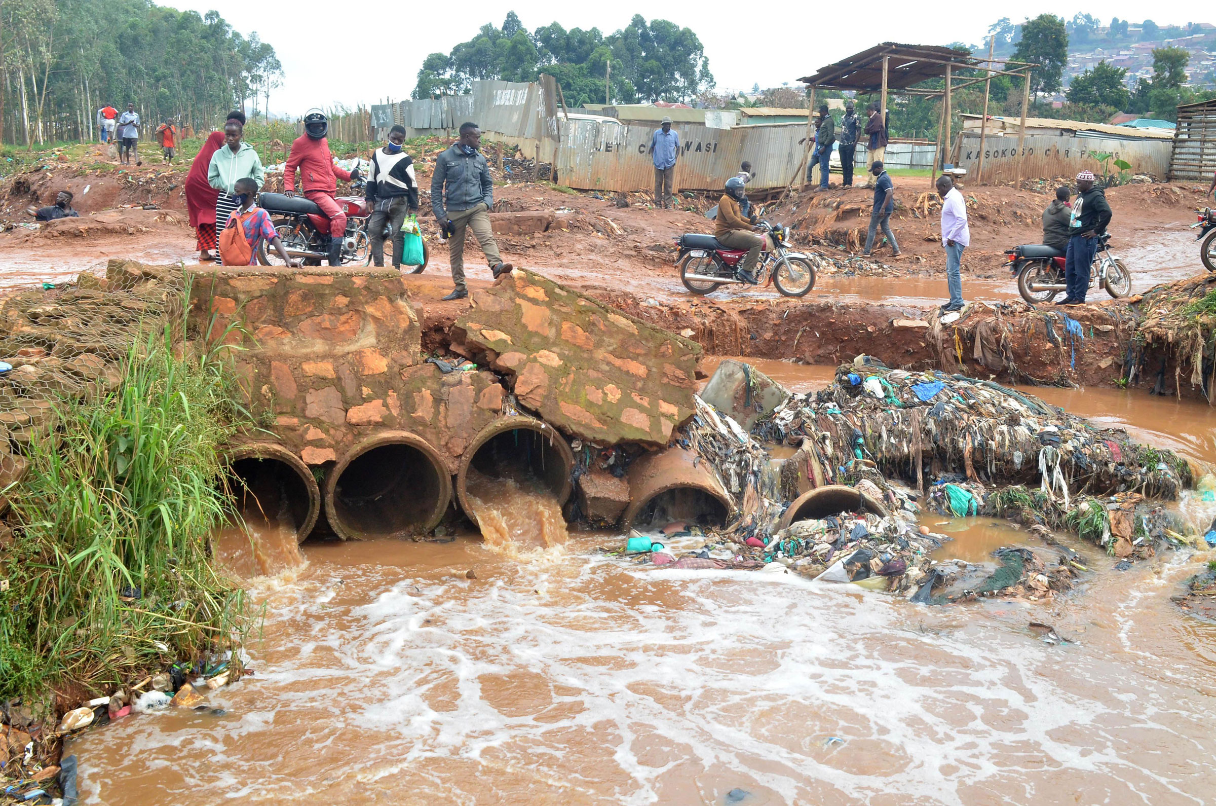 Mensen staan ​​op een beschadigde brug in de nasleep van een overstroming veroorzaakt door zware regenval in Kampala, Oeganda, aug.  9, 2021. (Nicholas Kajoba-Xinhua News Agency/Redux)