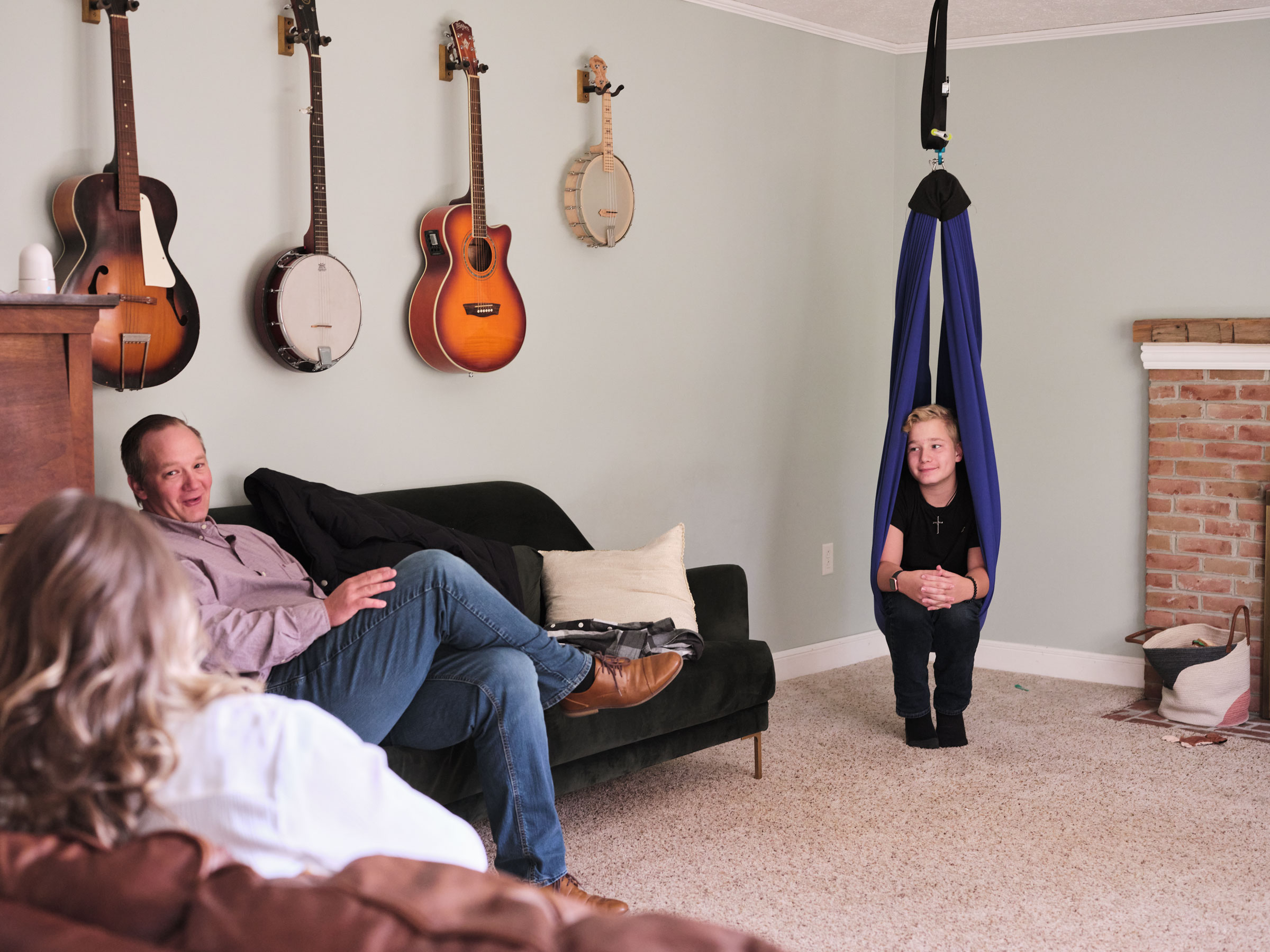 Ayden chats with his parents while sitting in a therapy swing in their home in Ohio. The swing helps Ayden manage some of his pain, allowing him to rest and recharge when he is tired or in pain. (Julie Renée Jones for TIME)