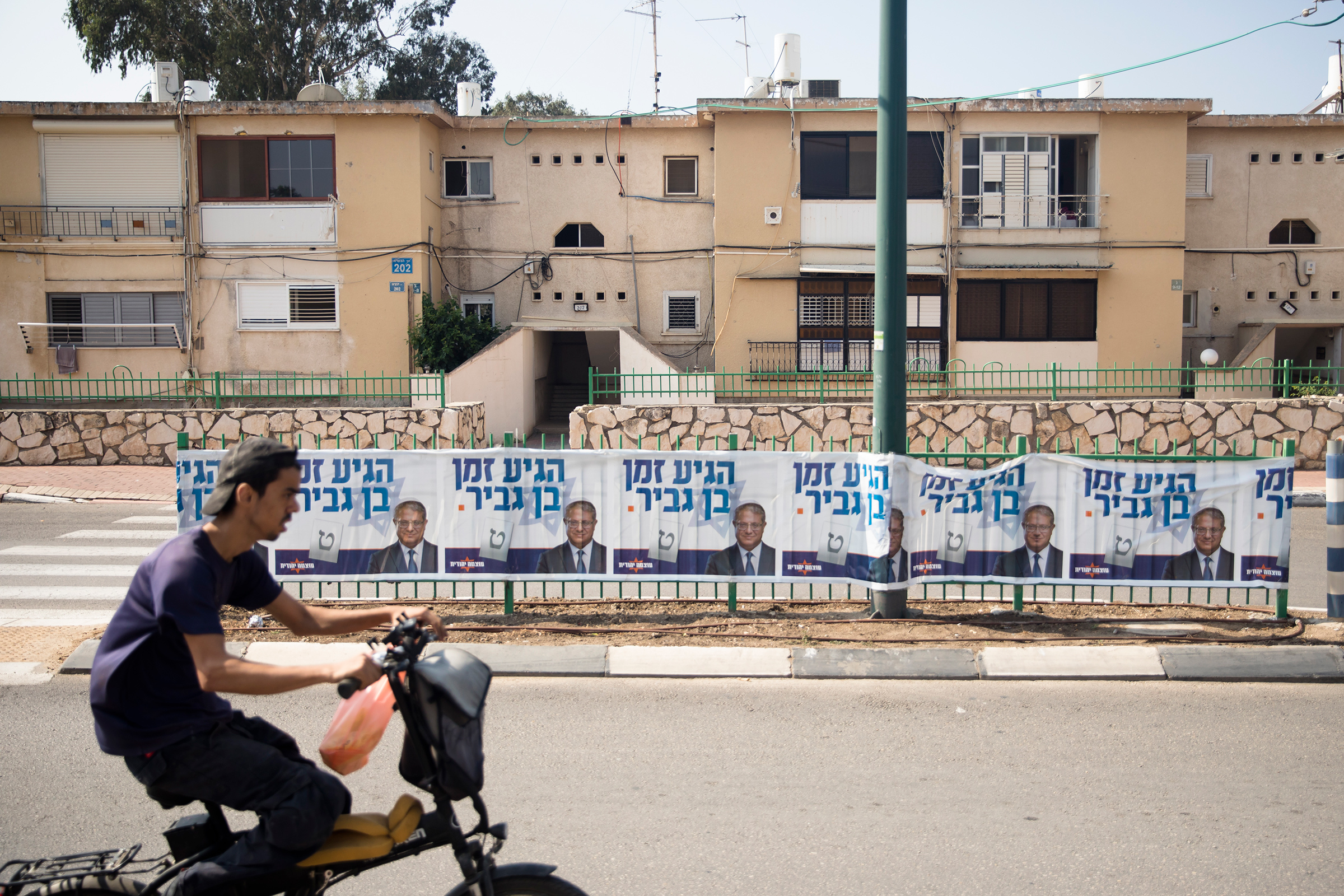A man rides by a 'Jewish Zionist' party campaign poster showing party member Itamar Ben-Gvir on Oct. 27 in Or Akiva, Israel. Israelis return to the polls on Nov. 1 for a fifth general election in four years. (Amir Levy—Getty Images)