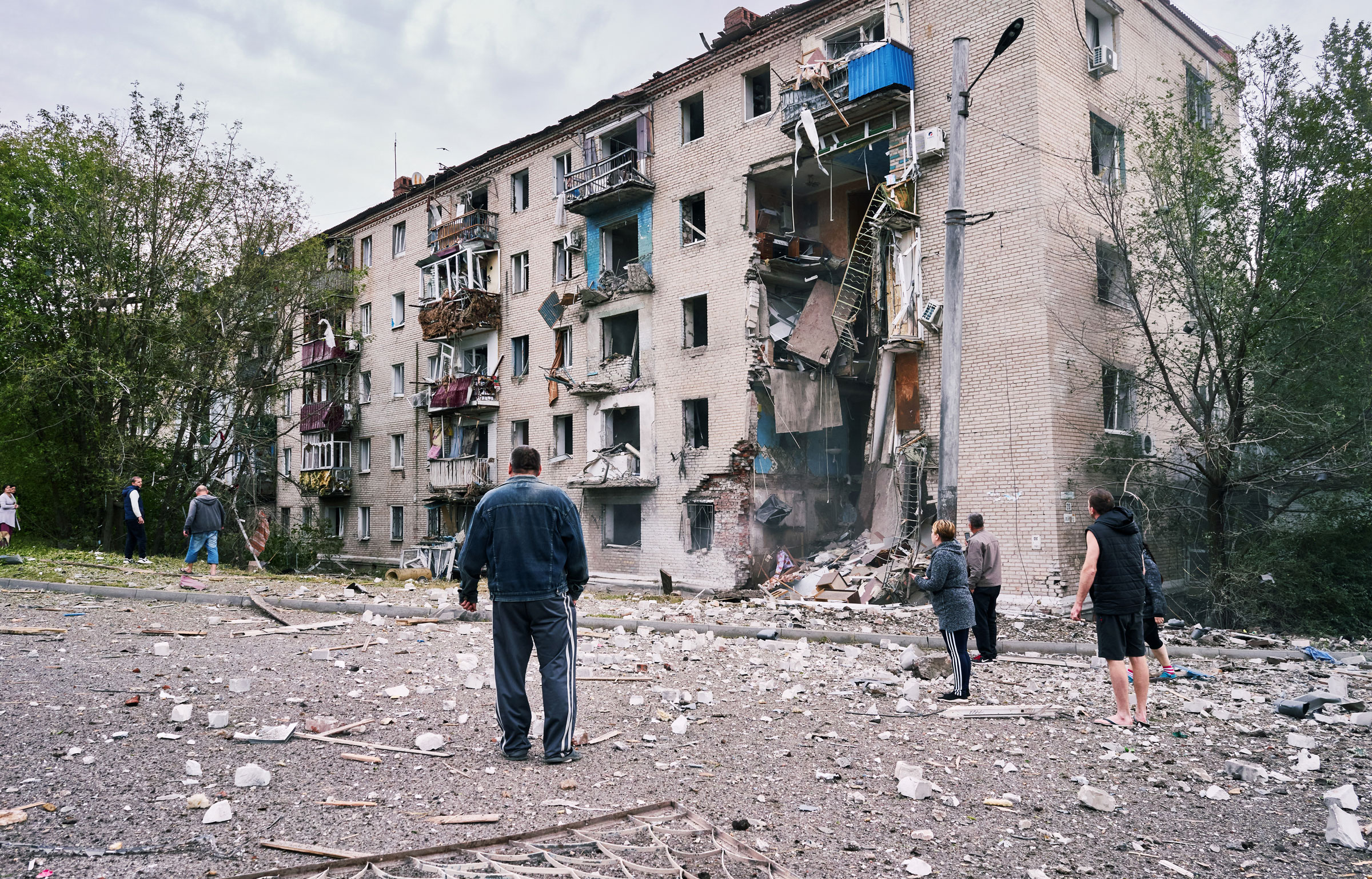 People gather to look at an apartment building damaged by two Russian rockets that hit earlier on Sept. 11, 2022, at around three o'clock in the afternoon, in Donetsk, Ukraine. (Iva Zimova—Panos Pictures/Redux)