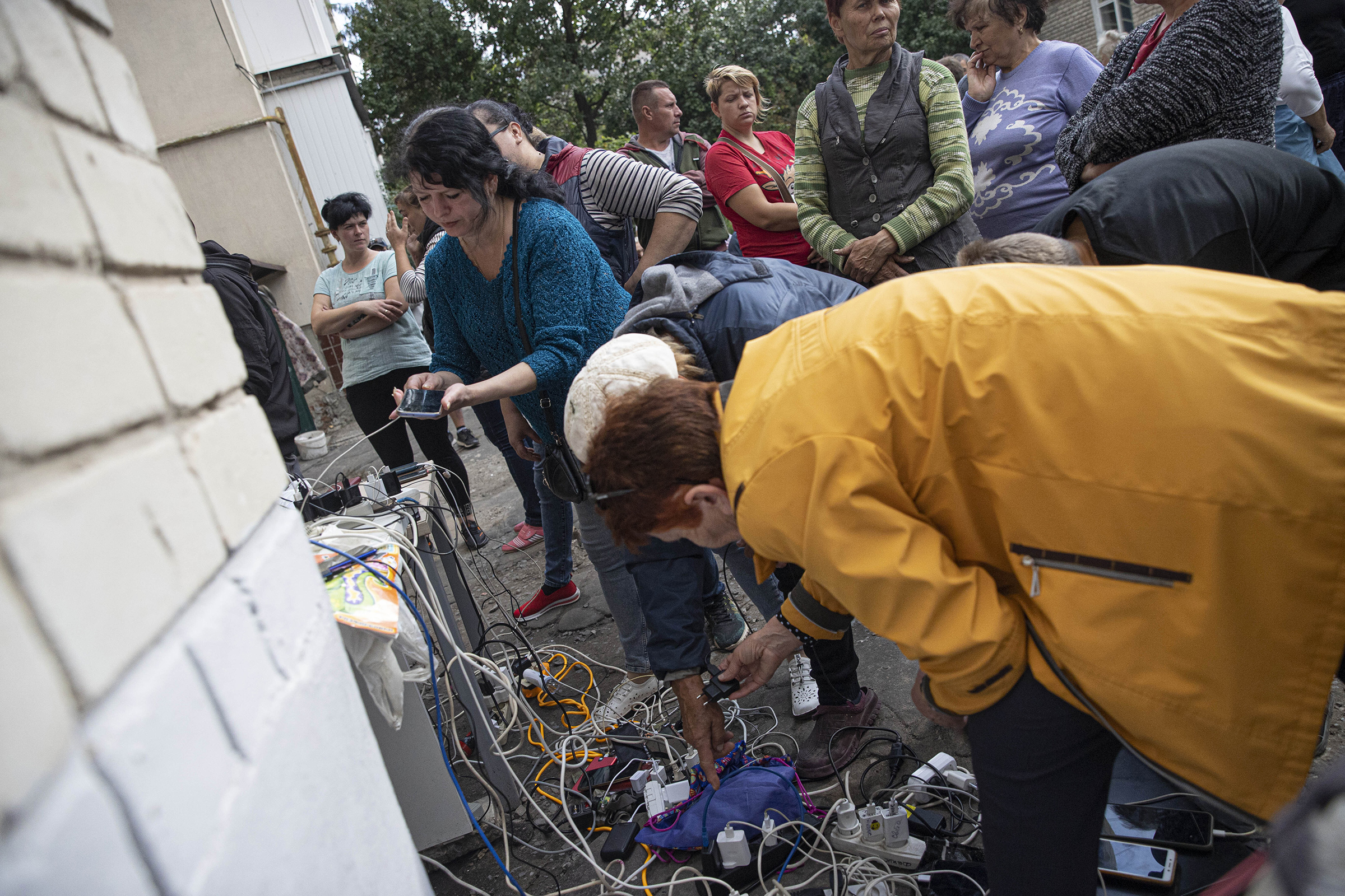 Ukrainian citizens charge their mobile phones and tablets from a generator supplied by Ukrainian soldiers after Russian Forces withdrawal from Izium as the Russia-Ukraine war continues, on Sept 18. Electricity, water and natural gas services are not available in Izium, located in Eastern Ukraine. (Metin Aktas—Anadolu Agency/Getty Images)