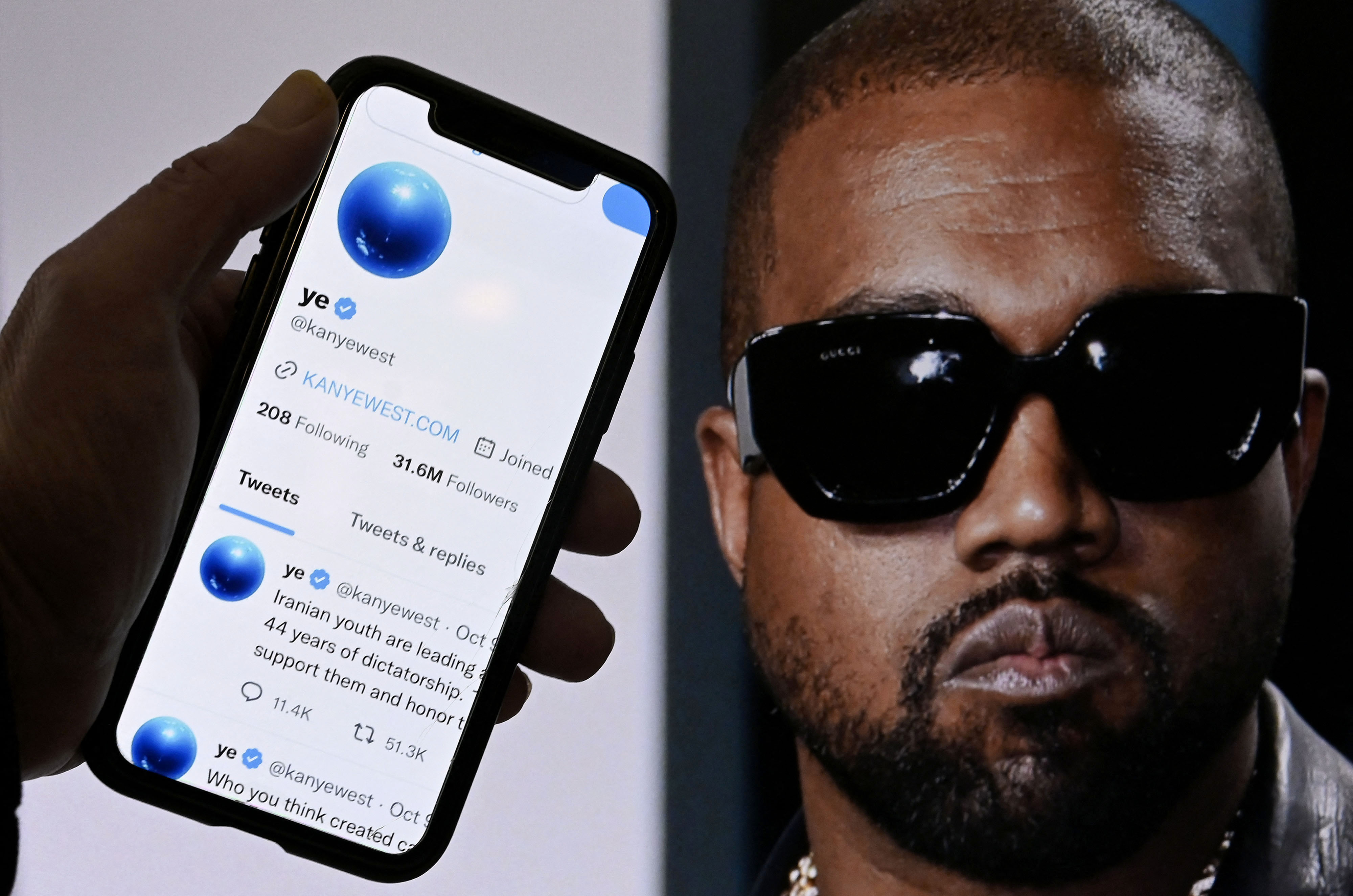 In this photo illustration, the Twitter account of Kanye West is displayed on a mobile phone with a photo of him shown in the background. (Olivier Douliery—AFP via Getty Images)