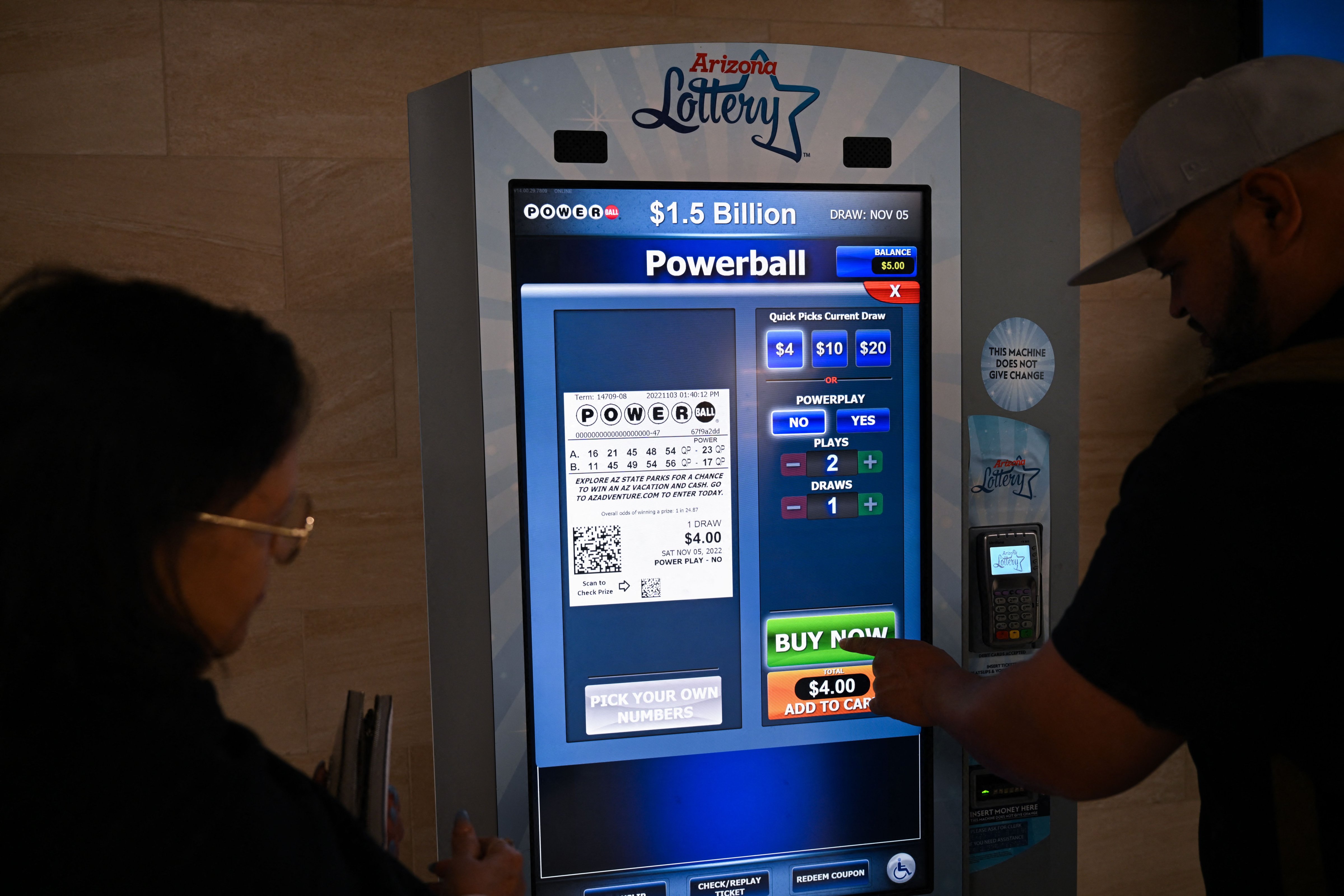 People purchase lottery tickets ahead of a PowerBall $1.5 Billon jackpot from a kiosk inside the Phoenix Sky Harbor International Airport (PHX) on November 3, 2022 in n Phoenix, Arizona. (Patrick T. Fallon—AFP/Getty Images)