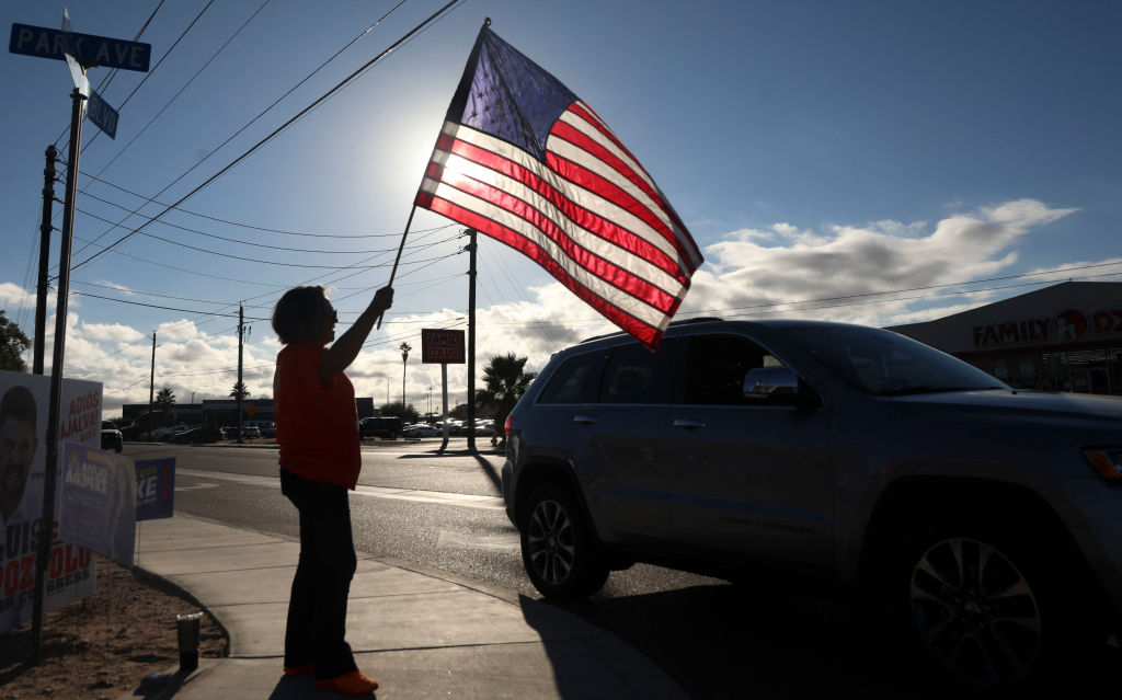 A woman waves an American flag to greet motorists as they head to vote in the midterm election at the Cesar Chavez Cultural Center in San Luis, Arizona on November 8, 2022. (Sandy Huffaker—AFP via Getty Images)