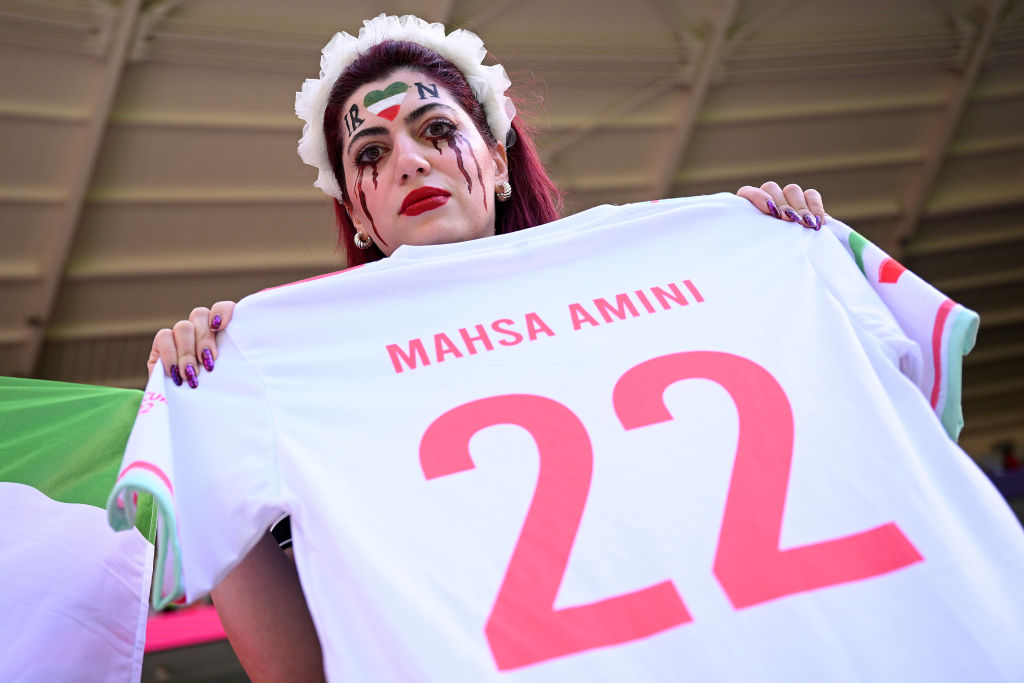 Fans hold up a shirt with the name of Mahsa Amini and a flag advocating for women's rights prior to the FIFA World Cup Qatar 2022 Group B match between Wales and Iran at Ahmad Bin Ali Stadium on Nov. 25, 2022 in Doha, Qatar. (Matthias Hangst—Getty Images)