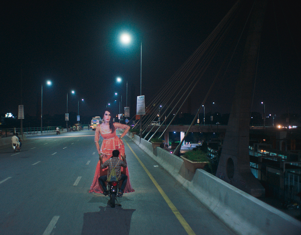 In a still from the Pakistani film "Joyland," Haider, played by Ali Junejo, is seen carrying a cutout of Biba, played by Alina Khan, while driving. (Courtesy of Saim Sadiq)