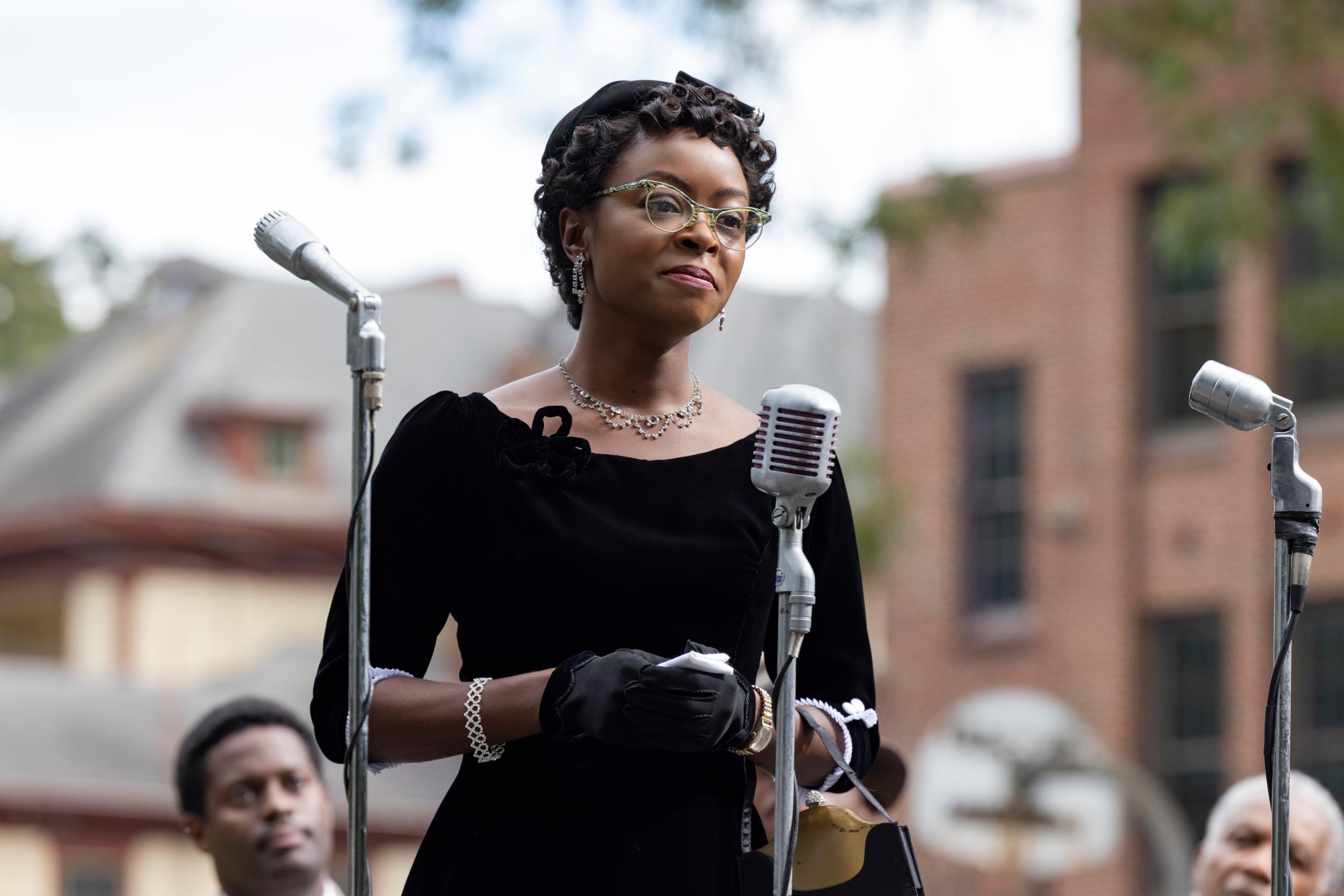Danielle Deadwyler as Mamie Till Mobley in TILL, directed by Chinonye Chukwu, dressed in a black dress and glasses, speaking into a microphone.