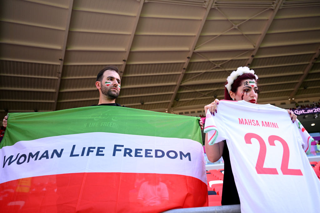 Fans hold up a shirt with the name of Mahsa Amini and a flag advocating for women's rights prior to the FIFA World Cup Qatar 2022 Group B game between Wales and IR Iran at Ahmad Bin Ali Stadium on Nov. 25, 2022 in Doha. (Matthias Hangst/Getty Images)