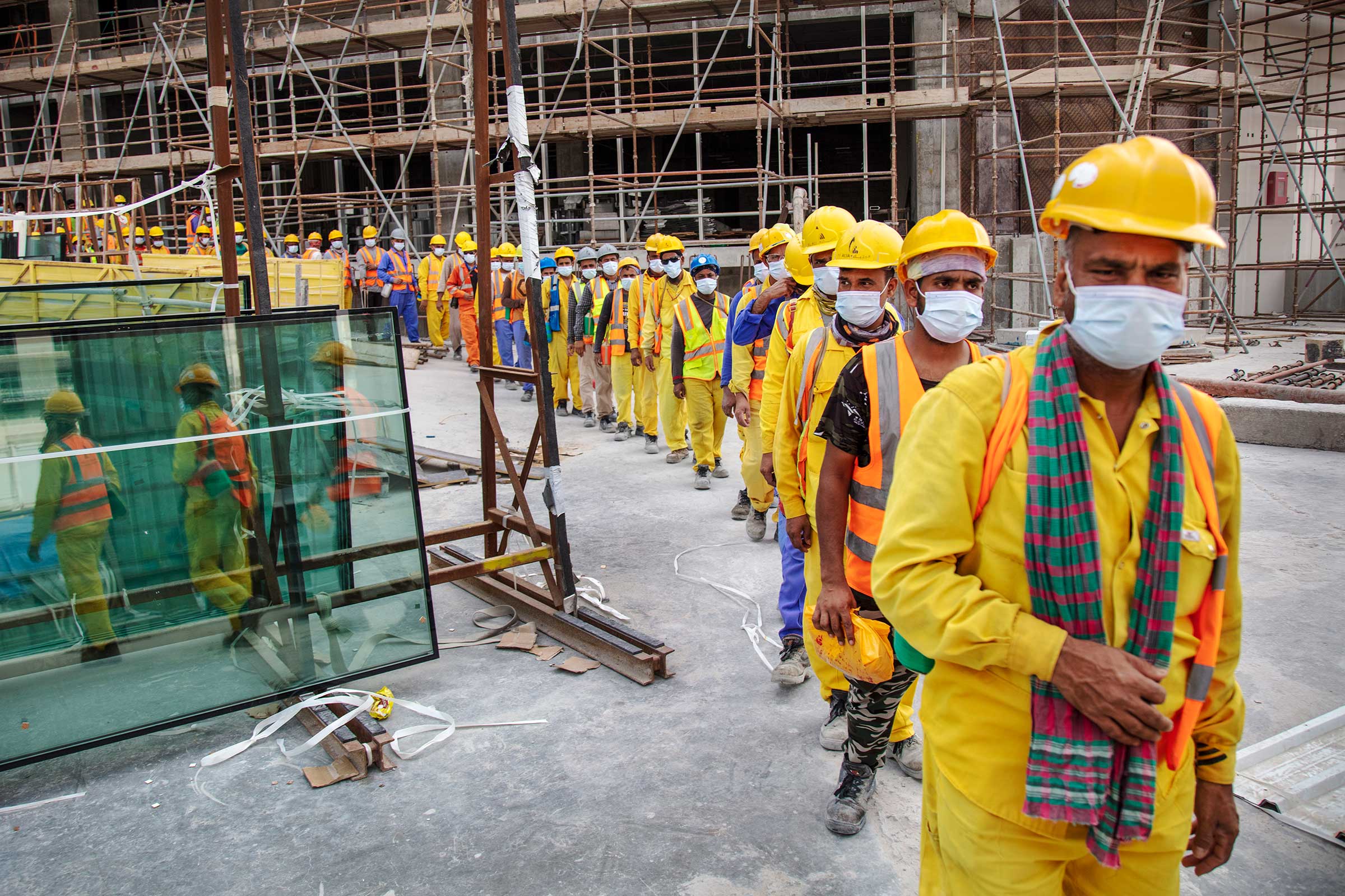 Workers at a Doha construction site lining up to get into buses to head to their sleeping quarters to rest during the mid-day heat, until the afternoon work started up again. (Ed Kashi—VII for TIME)