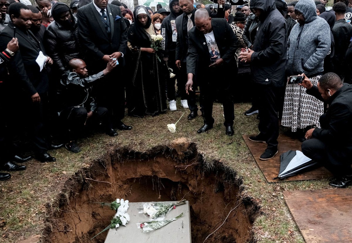 Peter Lyoya throws a flower into the grave of his son Patrick Lyoya, an unarmed Black man who was fatally shot and killed by a Grand Rapids Police officer during a traffic stop on April 4, during the funeral in Grand Rapids, Mich., on April 22.