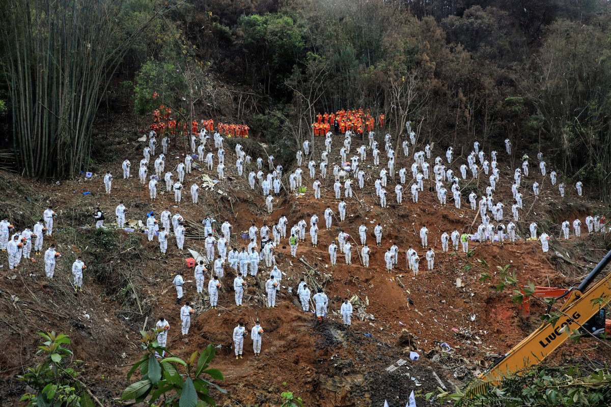 Rescuers stand in a silent tribute for victims at the site of the China Eastern Airlines plane crash in Tengxian county, Wuzhou city, in China's southern Guangxi region, on March 27.