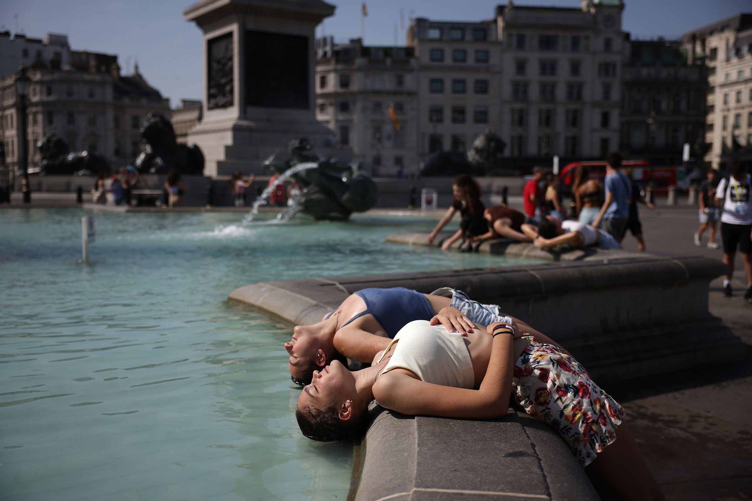 Two women dip their heads into the fountain to cool off in Trafalgar Square in London on July 19. (Dan Kitwood—Getty Images)