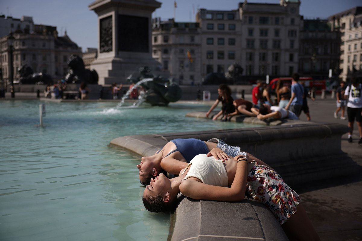 Two women dip their heads into the fountain to cool off in Trafalgar Square in London on July 19.