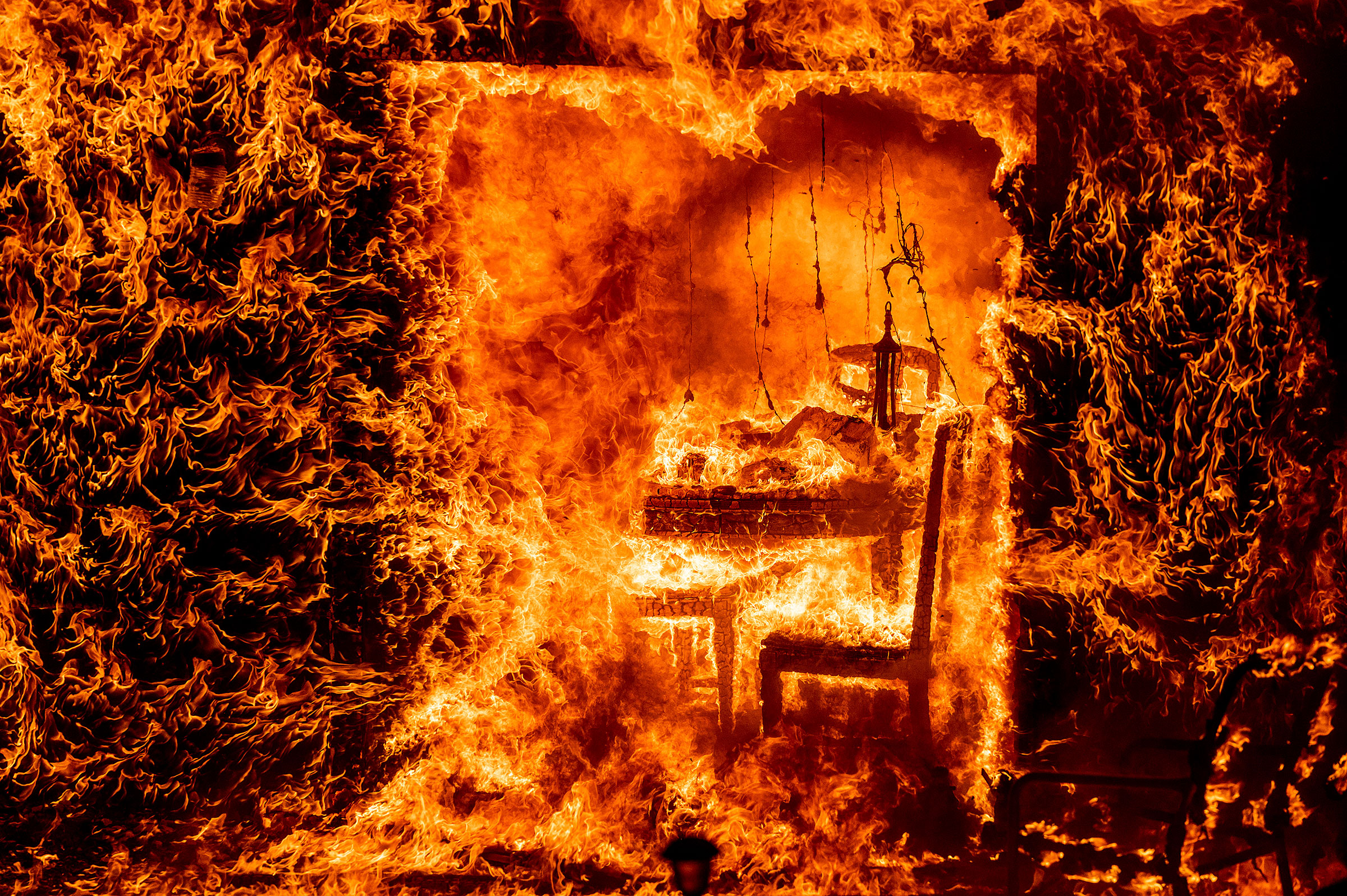 Flames engulf a chair inside a burning home as the Oak Fire burns in Mariposa County, Calif., on July 23. (Noah Berger—AP)
