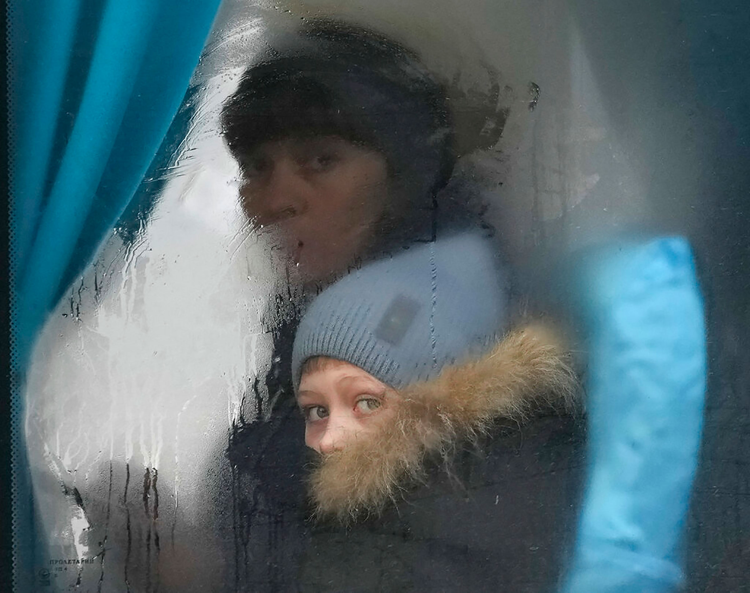 A woman and child peer out of the window of a bus as they leave Sievierodonetsk, Luhansk region, Ukraine, on Feb. 24. (Vadim Ghirda—AP)