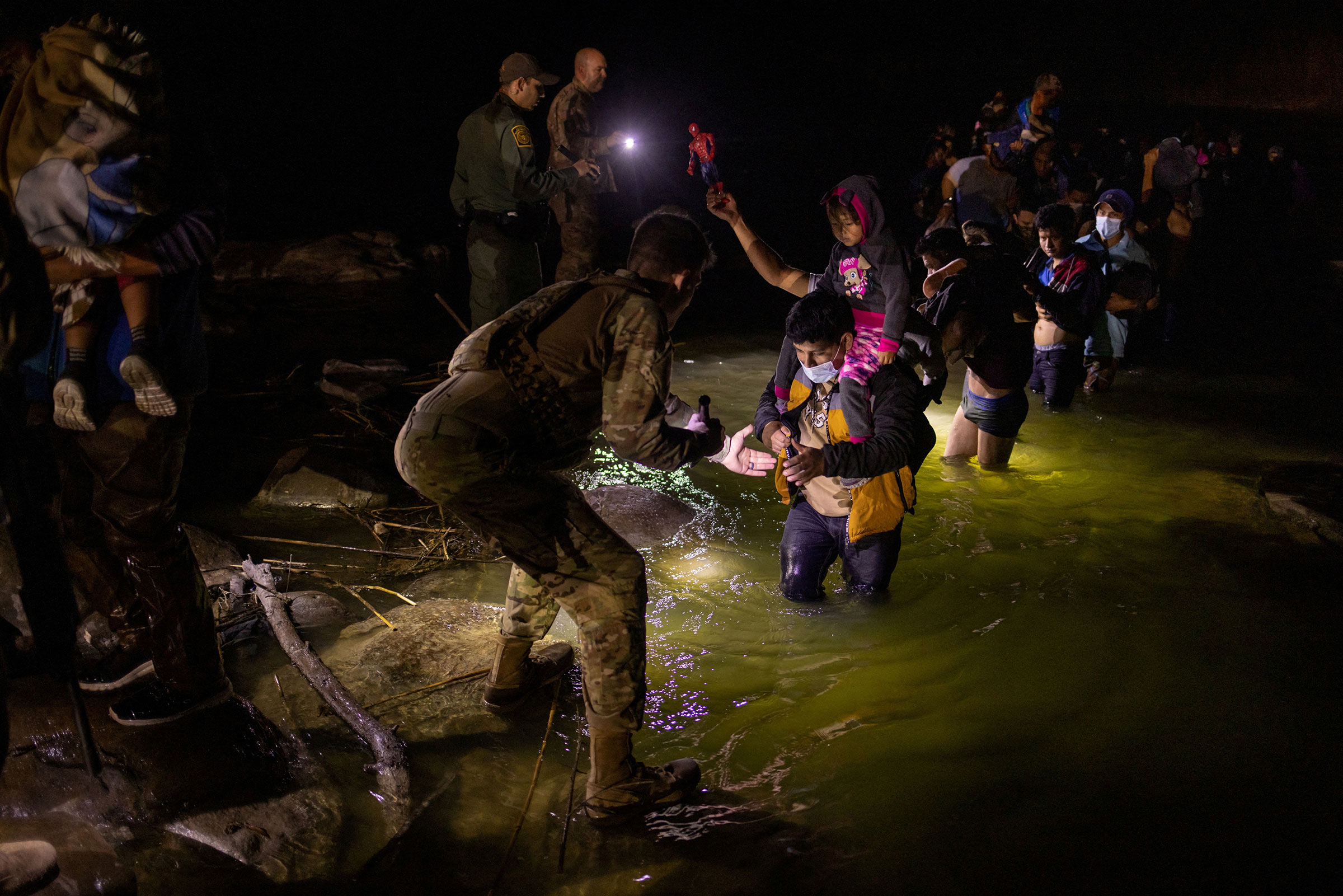 Border patrol agents and members of the Texas Army National Guard light the path as asylum-seeking migrants from Central and South America wade through the Rio Grande river into the United States from Mexico, in Roma, Texas, on March 4.