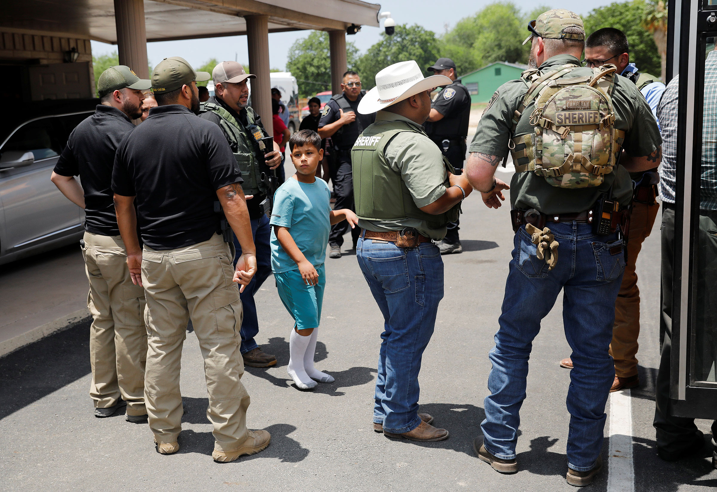 A child gets on a school bus as law enforcement personnel guard the scene of a shooting near Robb Elementary School in Uvalde, Texas, on May 24. (Marco Bello—Reuters)