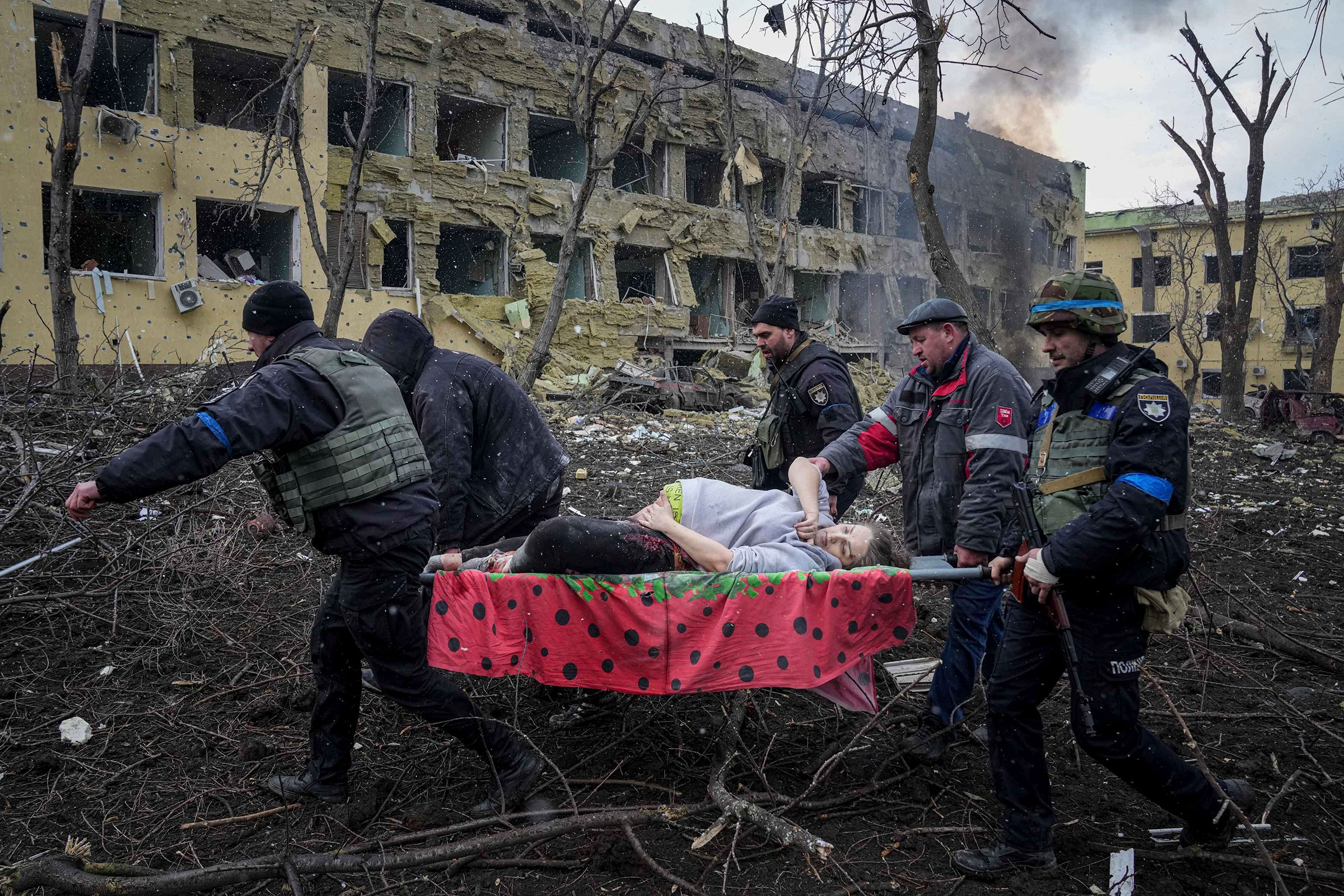 Ukrainian emergency employees and volunteers carry an injured pregnant woman from a maternity hospital damaged by shelling in Mariupol, Ukraine, on March 9. The baby was born dead. Half an hour later, the mother died too. (Evgeniy Maloletka—AP)