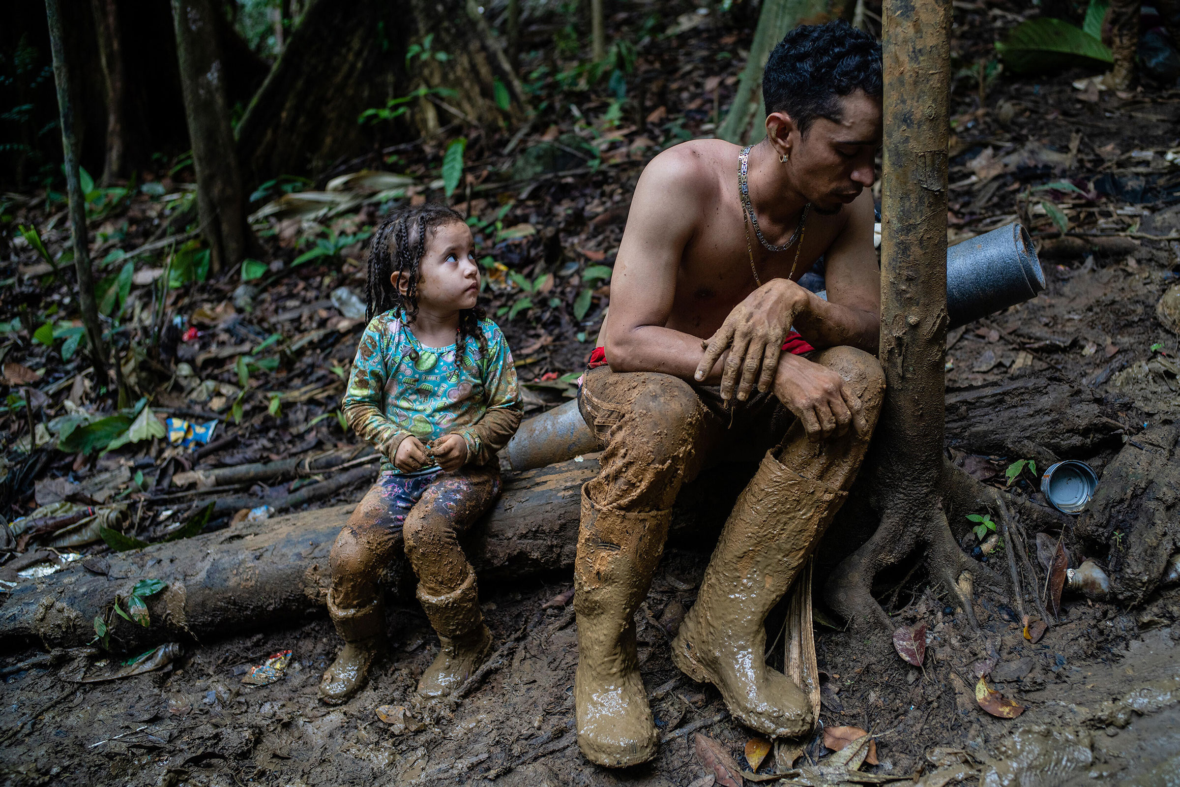 An exhausted man and child rest in the Darien Gap, with a week of walking still ahead across the 66-mile stretch of jungle terrain between Colombia and Panama, on Sept. 23. Two crises are converging as record numbers of Venezuelans risk the deadly trek to reach the U.S. border: the economic and humanitarian disaster underway in South America and the bitter fight over immigration policy in Washington. (Federico Rios—The New York Times/Redux)
