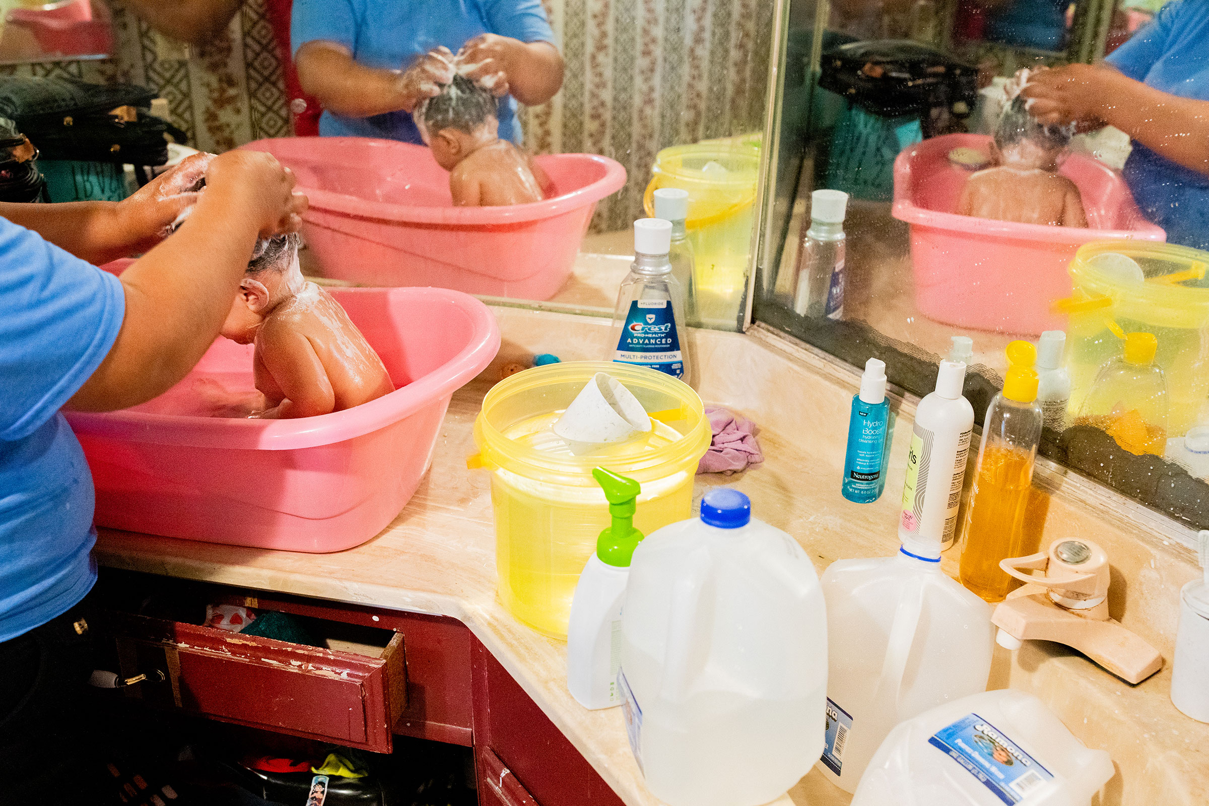 Cecilia Cruz bathes her daughter Daleyda with bottled water that she preheated beforehand inside the family’s trailer at the Oasis Mobile Home Park in Thermal, Calif. on June 25. In 2019 the Environmental Protection Agency found that the park’s water was contaminated with arsenic at nearly 10 times the allowable limit and residents have since been warned not to use it for drinking, cooking, bathing, or brushing their teeth.