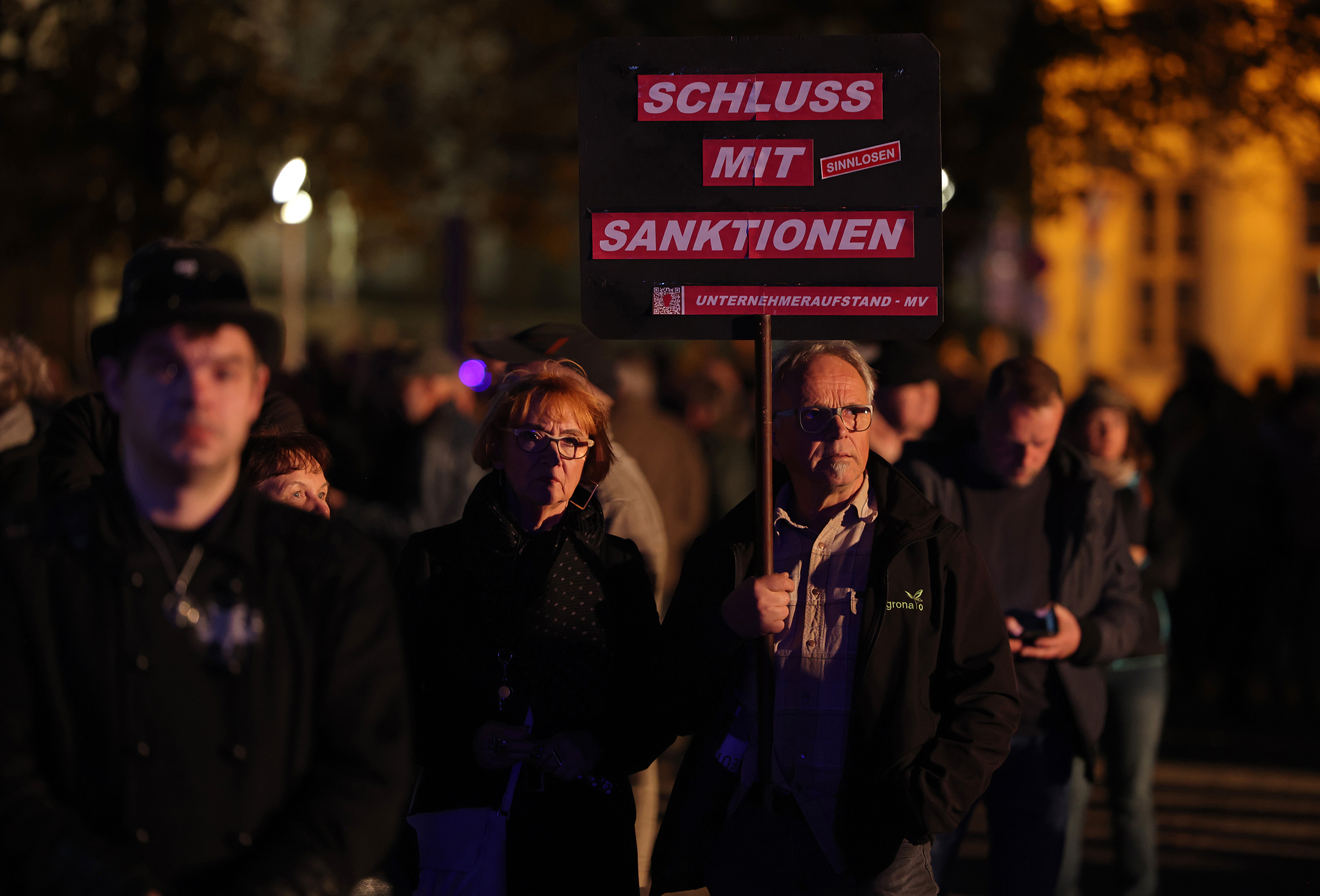 Un homme tient une pancarte indiquant : "Assez avec les sanctions" avant un lundi soir "flâner" ("Spaziergang") des manifestants le 24 octobre à Schwerin, en Allemagne.  (Sean Gallup—Getty Images)