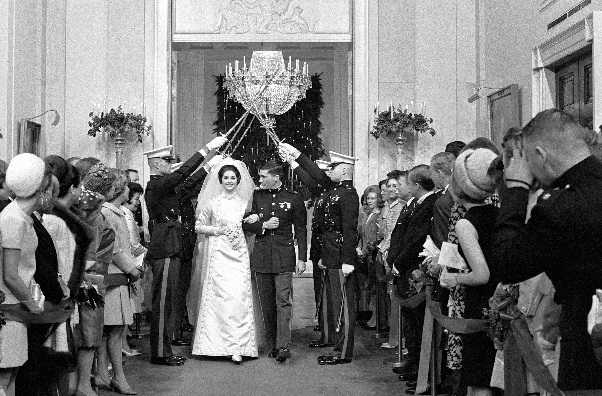 Charles Robb and Lynda Johnson, daughter of President Lyndon B. Johnson, walk through an arch of drawn swords as they leave the East Room of the White House following their wedding ceremony, Dec. 9, 1967. (Bettmann Archive/Getty Images)