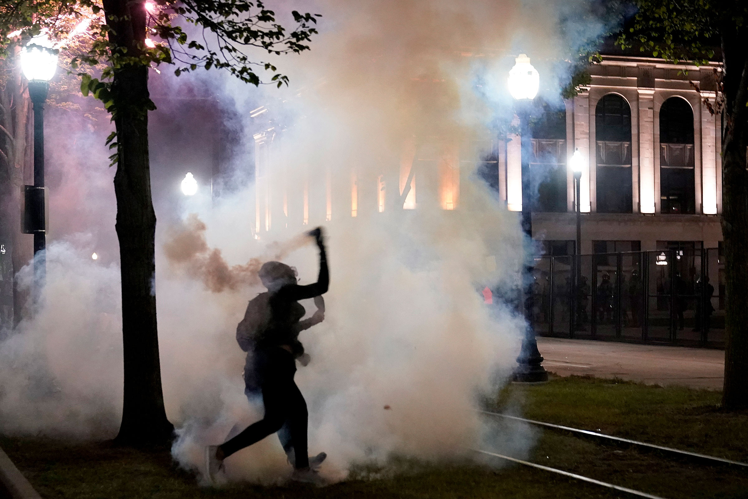 A protester throws back a can of smoke toward law enforcement during clashes outside the Kenosha County Courthouse on Aug. 25, 2020, in Kenosha, Wis. Protests continue following the police shooting of Jacob Blake two days earlier.