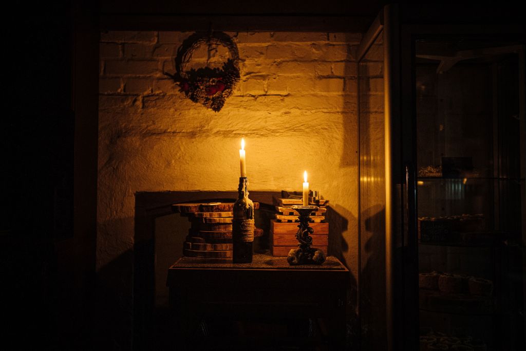Candles light a restaurant during a power cut in downtown Kyiv on December 6, 2022, amid the Russian invasion of Ukraine. - With temperatures dipping below zero, repeated Russian attacks have left Ukraine's energy grid teetering on the brink of collapse and have disrupted power and water supplies to millions over recent weeks. (Dimitar DILKOFF- AFP)