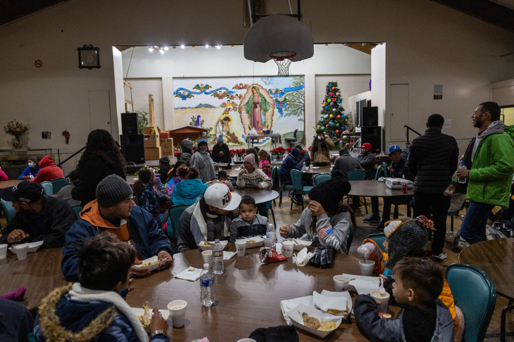 Immigrants eat breakfast inside an overnight migrant shelter run by Sacred Heart Church on December 18, 2022 in El Paso, Texas. (John Moore—Getty Images)