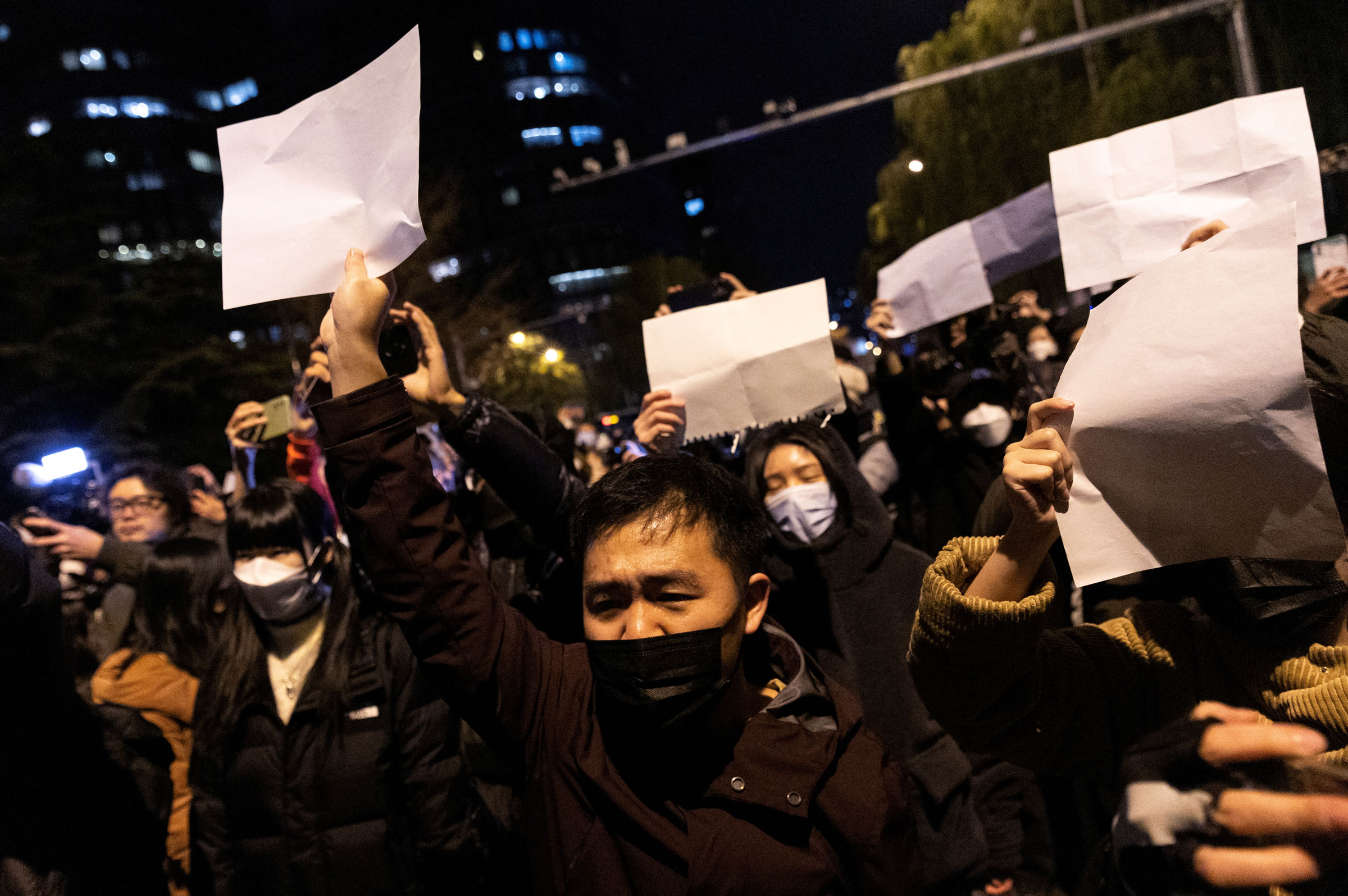 People hold white sheets of paper in protest over COVID-19 restrictions, after a vigil for the victims of a fire in Urumqi, as outbreaks of COVID-19 continue, in Beijing, China, on Nov. 28, 2022. (Thomas Peter—Reuters)