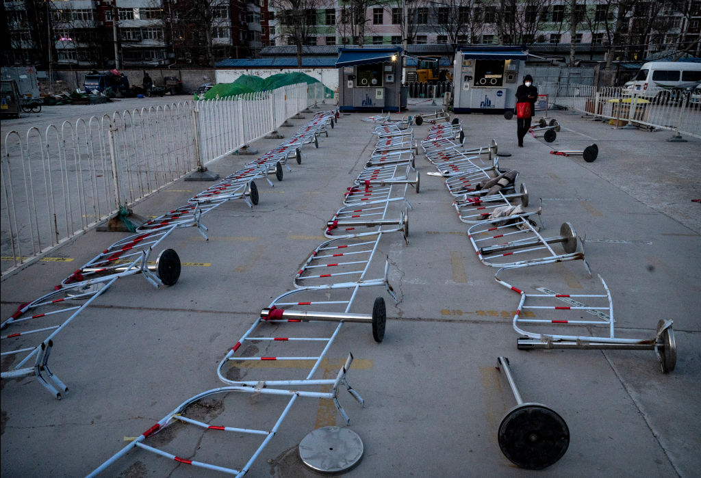 A woman walks past barricades as they are scattered on the ground at a COVID-19 testing site, on December 19, 2022 in Beijing, China.  (Kevin Frayer—Getty Images)