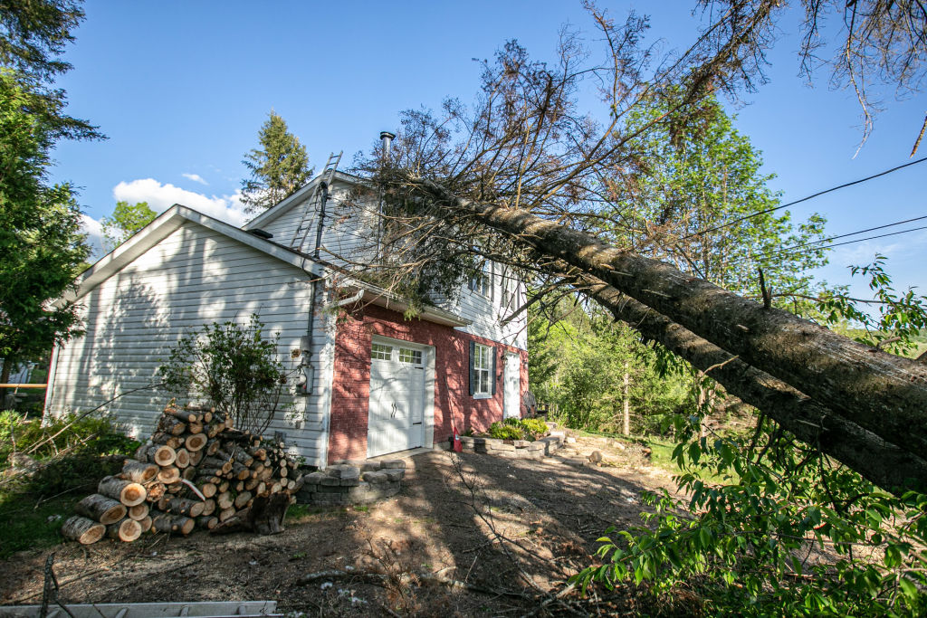 A tree leaning on the rooftop of a damaged house after a "derecho" storm in Saint-Hippolyte, Quebec, on May 21, 2022. (Giordanno Brumas—SOPA Images/LightRocket/ Getty Images)