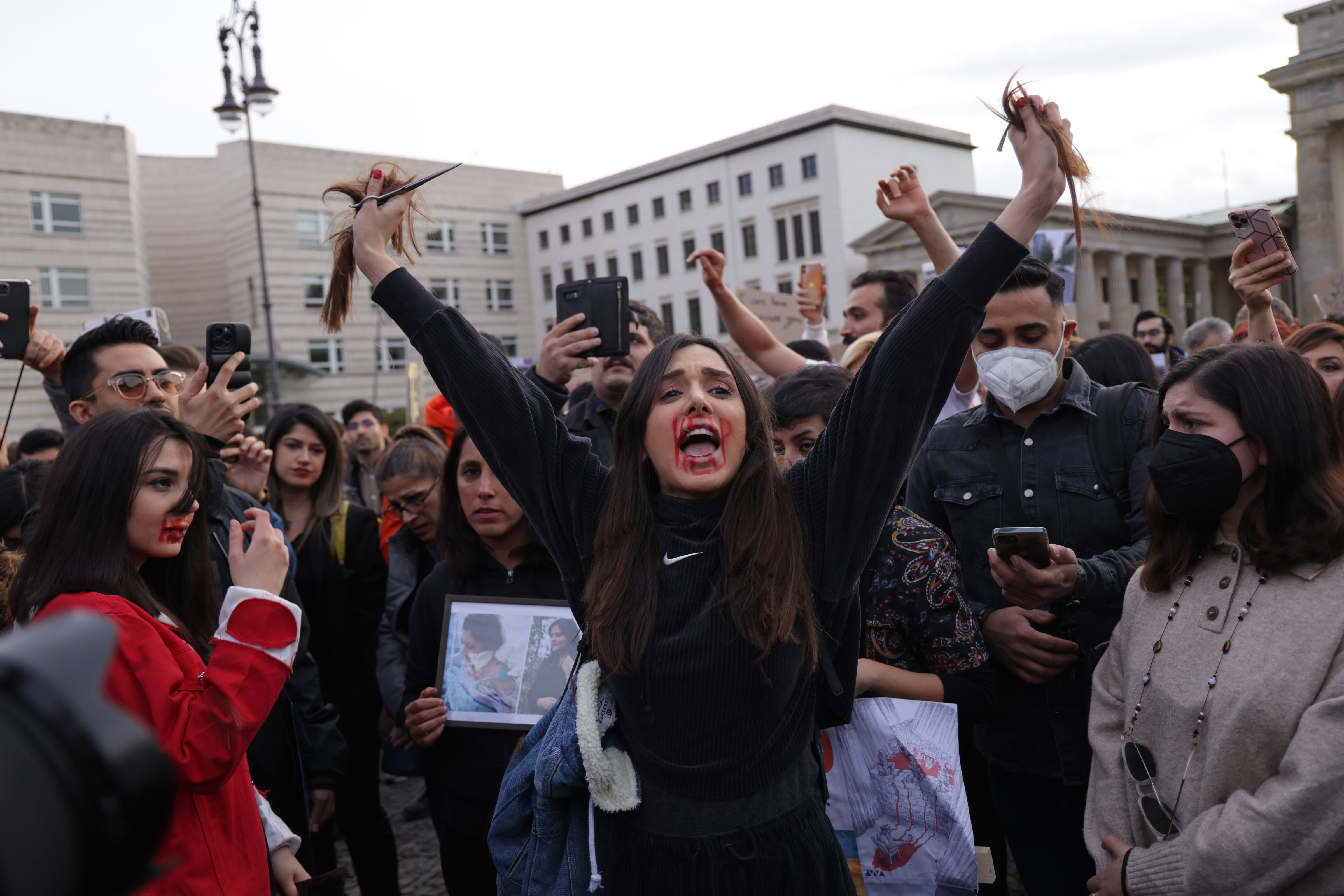 A protester yells after cutting her hair with scissors as an act of solidarity with women in Iran during a demonstration on September 23, 2022 in Berlin, Germany. (Sean Gallup-Getty Images)