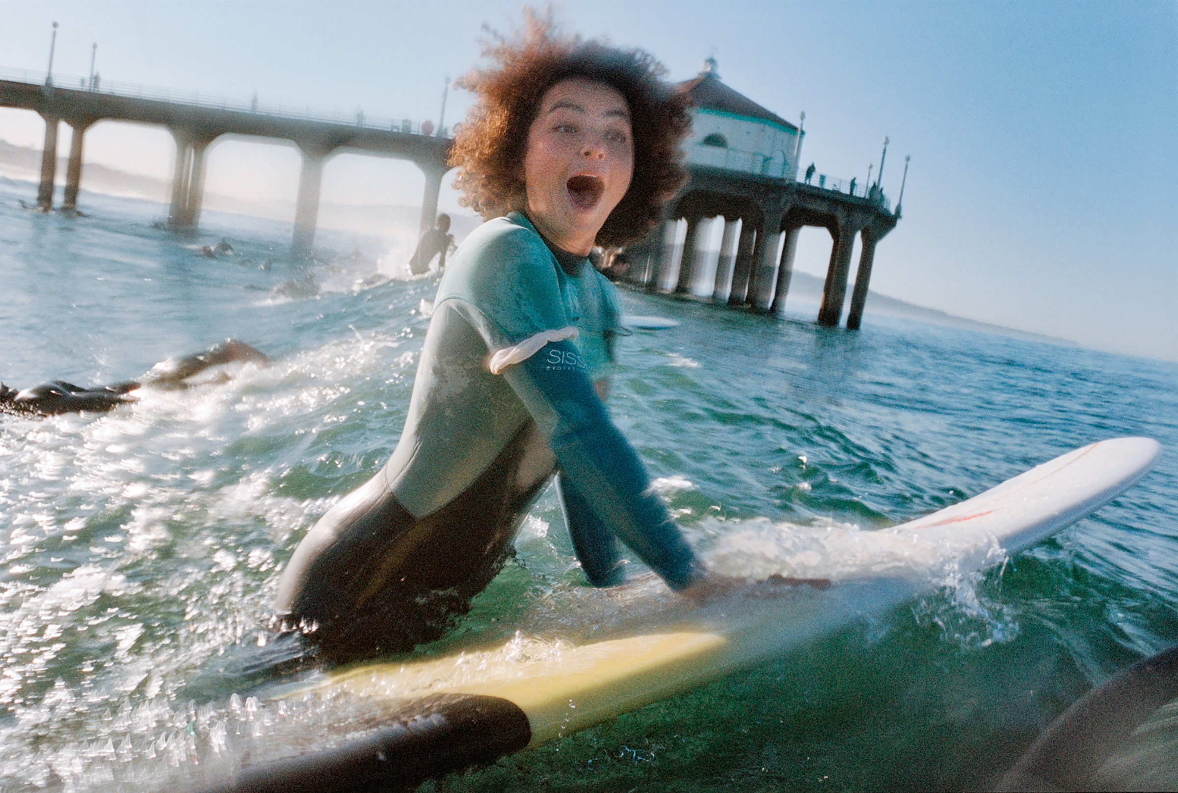 Kimiko Russell-Halterman, a surfer and waterwoman, pops up over a wave during the Black Sand paddle out near the Manhattan Beach Pier in Los Angeles, Feb. 2021.