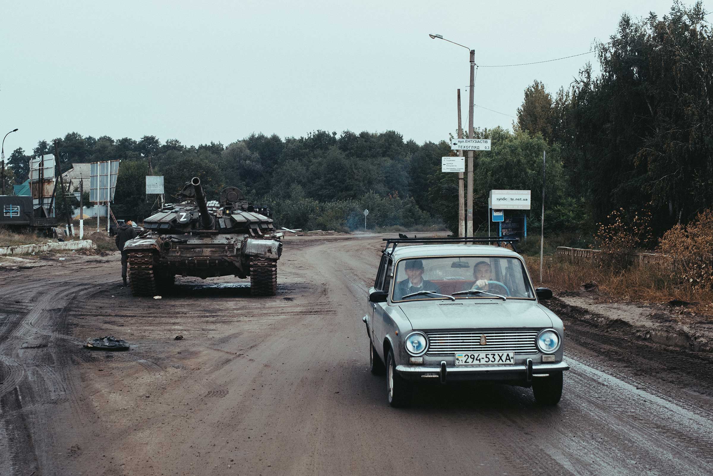 A car passes an abandoned Russian military vehicle in Izyum. (Maxim Dondyuk)