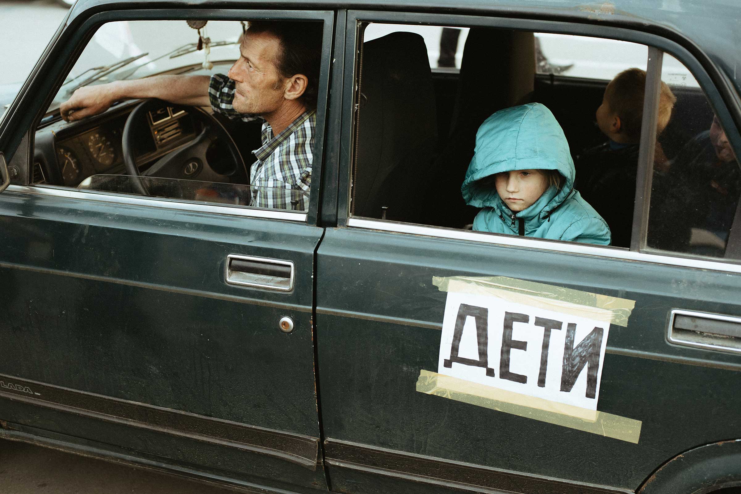 An evacuating family in their car, with a sign that reads “children”. (Maxim Dondyuk)