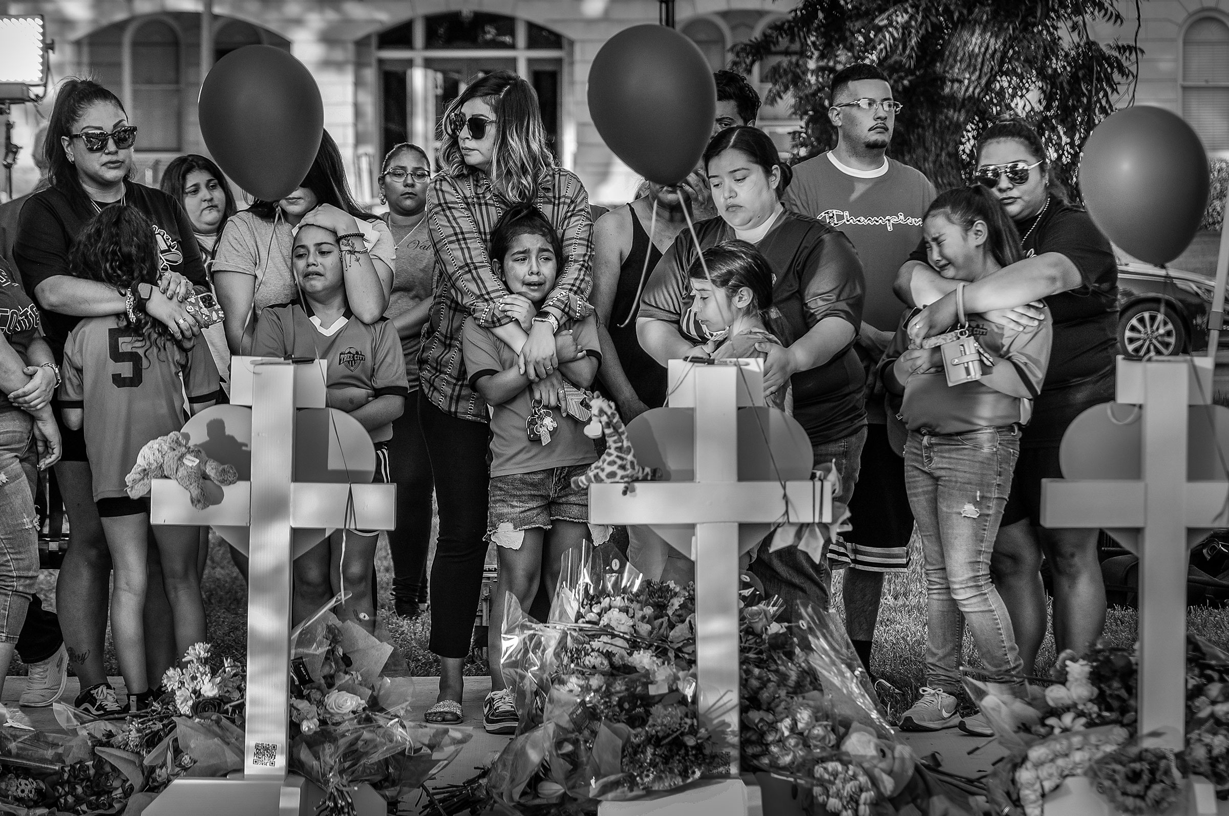 Local children and their parents react to a makeshift memorial in downtown Uvalde, nearby Robb Elementary School, on May 26. (David Butow—Redux)