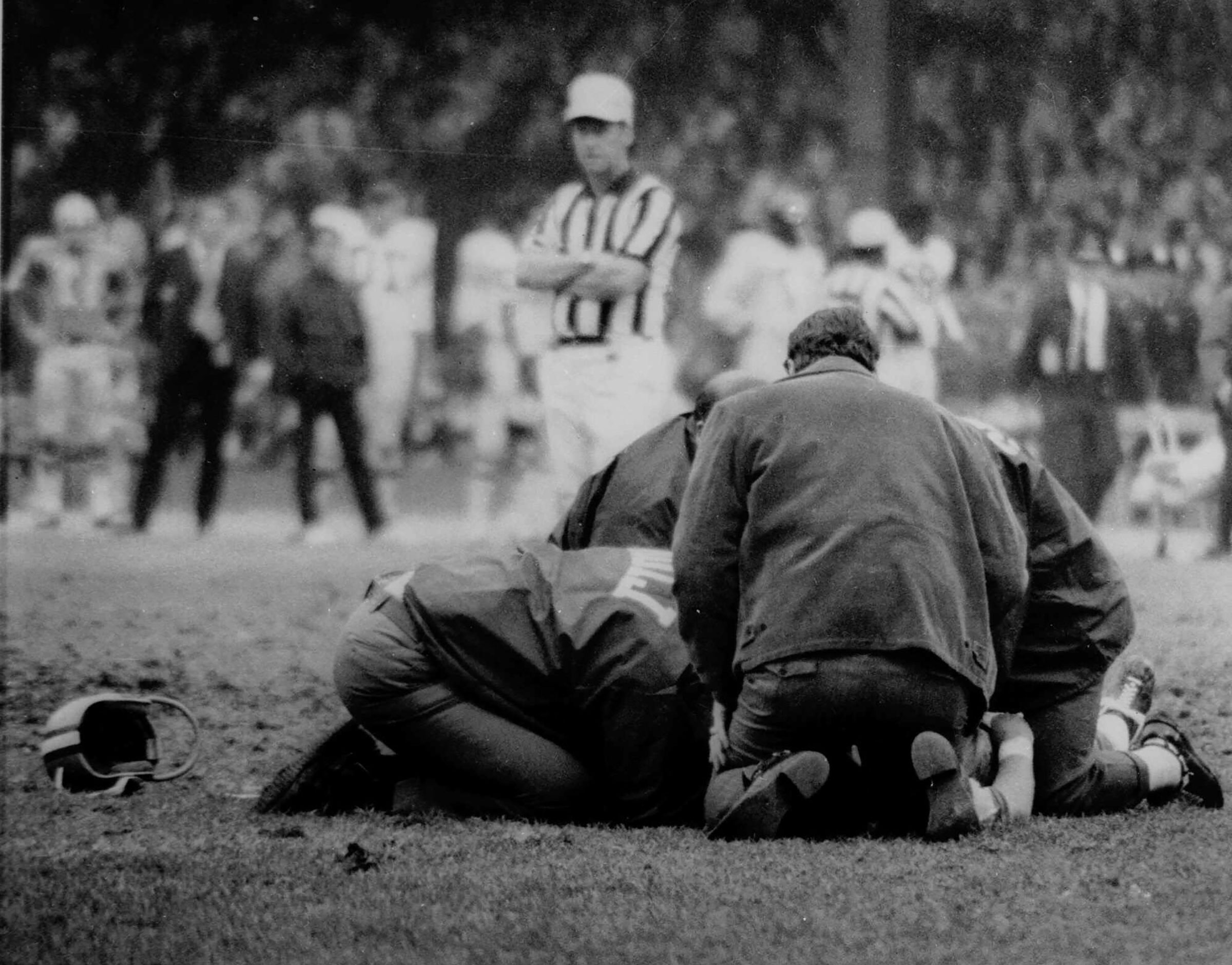 El médico del equipo, Edwin Gis, a la derecha, atiende a Chuck Hughes poco después de que colapsara durante un partido entre los Detroit Lions y los Chicago Bears el 25 de octubre de 1971. Hughes murió más tarde en un hospital de Detroit.  (AP)