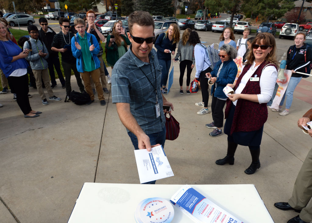 Fairview civics teacher, Dan Niedringhaus, puts a election ballot in a dropbox at the South Boulder Recreation Center on Thursday as Fairview High School students and staff who were old enough to vote marched from their school over their lunch hour to drop off their ballots in early voting on October 25, 2018 in Boulder Colorado. (Cliff Grassmick-Digital First Media/Boulder Daily Camera)