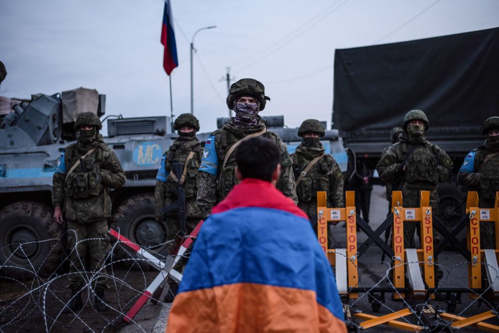 A protester wearing the Armenian national flag stands in front of Russian peacekeepers blocking the road outside Stepanakert, Nagorno-Karabakh region on Dec. 24, 2022. (Davit Ghahramanyan—AFP via Getty Images)