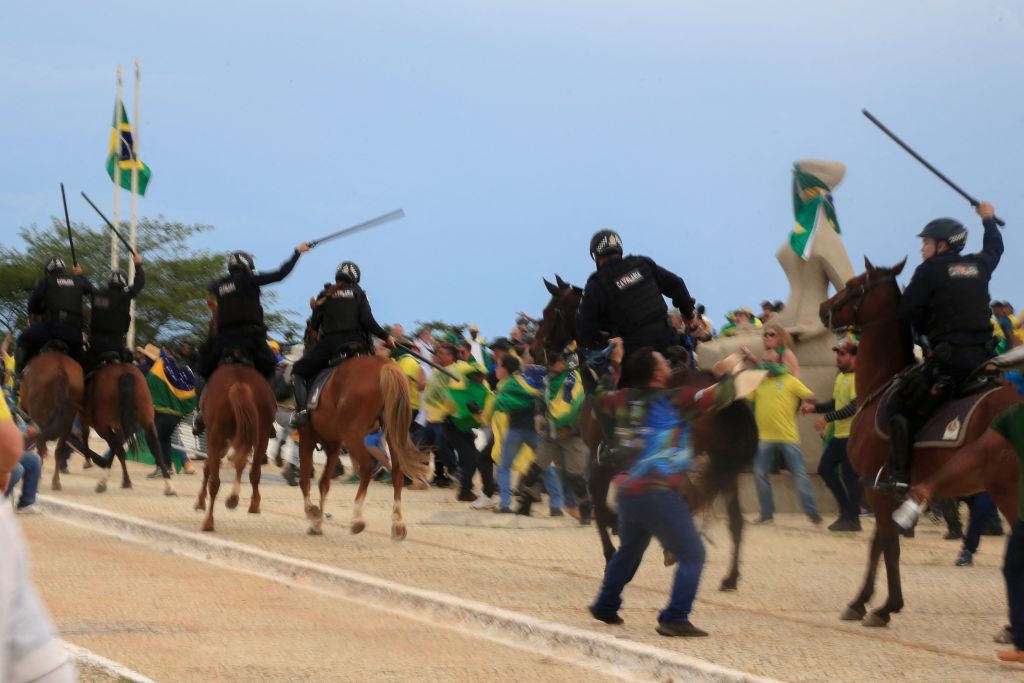 Supporters of Brazilian former President Jair Bolsonaro clash with riot police as they invade Planalto Presidential Palace in Brasilia on January 8, 2023. - Hundreds of supporters of Brazil's far-right ex-president Jair Bolsonaro broke through police barricades and stormed into Congress, the presidential palace and the Supreme Court Sunday, in a dramatic protest against President Luiz Inacio Lula da Silva's inauguration last week. (SERGIO LIMA-AFP via Getty Images)