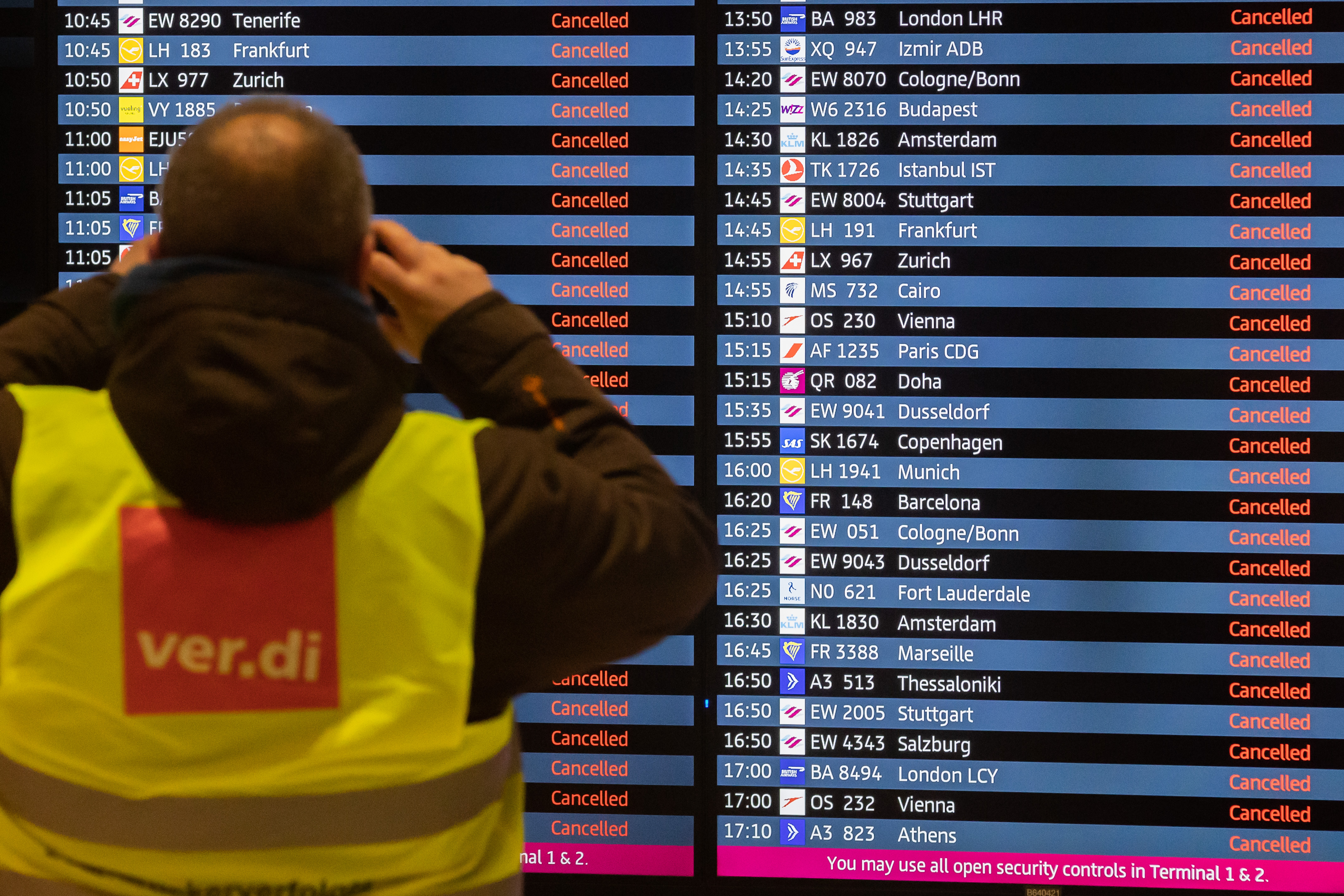 A man wearing a Verdi vest takes a photo of a display board showing all flights as canceled during a warning strike at Berlin-Brandenburg BER Airport, Jan. 25, 2023. (Christoph Soeder—picture alliance/Getty Images)