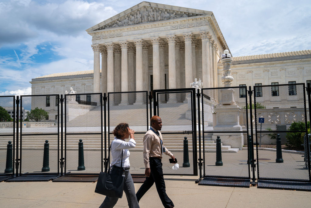 Two civilians walk past the fenced off United States Supreme Court building July 28, 2022 in Washington, DC. The building has been the site for numerous demonstrations and protests since the U.S. Supreme Court decision to end federal abortion rights protections. (Robert Nickelsberg—Getty Images)