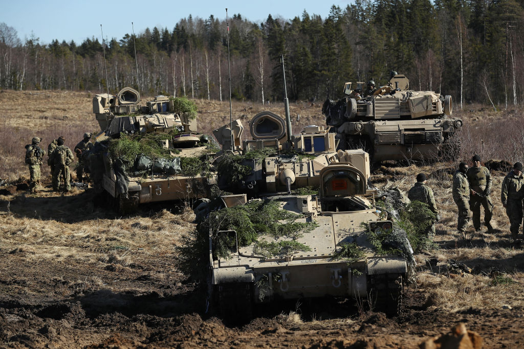 Members of Chaos Company, 1-68 Armor Battalion of the 3rd Brigade Combat Team, 4th Infantry Division, stand near their M2A3 Bradley fighting vehicles and an M1 Abrams tank following a joint military combat exercise with Estonian soldiers on March 23, 2017 near Tapa, Estonia. (Sean Gallup—Getty Images)