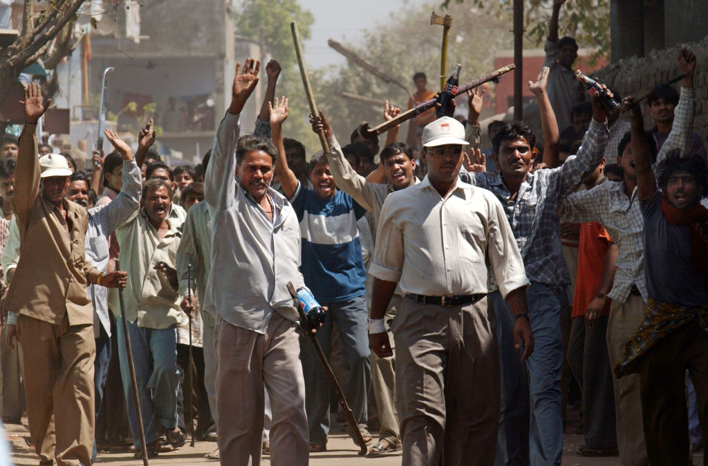 401733 09: Hindistan Hızlı Tepki Gücü memurları, 1 Mart 2002'de Hindistan'ın Ahmadabad kentinde küçük bir Müslüman grubuna saldırmalarını engelledikten sonra kılıç ve sopa kullanan bir Hindu çetesi geri çekildi.  (Ami Vitale—Getty Images)
