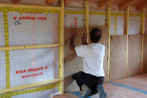 Wooden structure of house under construction. Construction worker installing insulation.