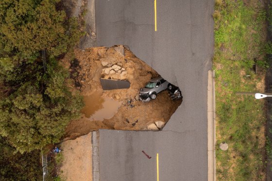 In an aerial view, a car and a pickup truck are seen inside a sinkhole as another storm created by a series of atmospheric rivers inundates Calif. in Los Angeles on Jan. 10, 2023.